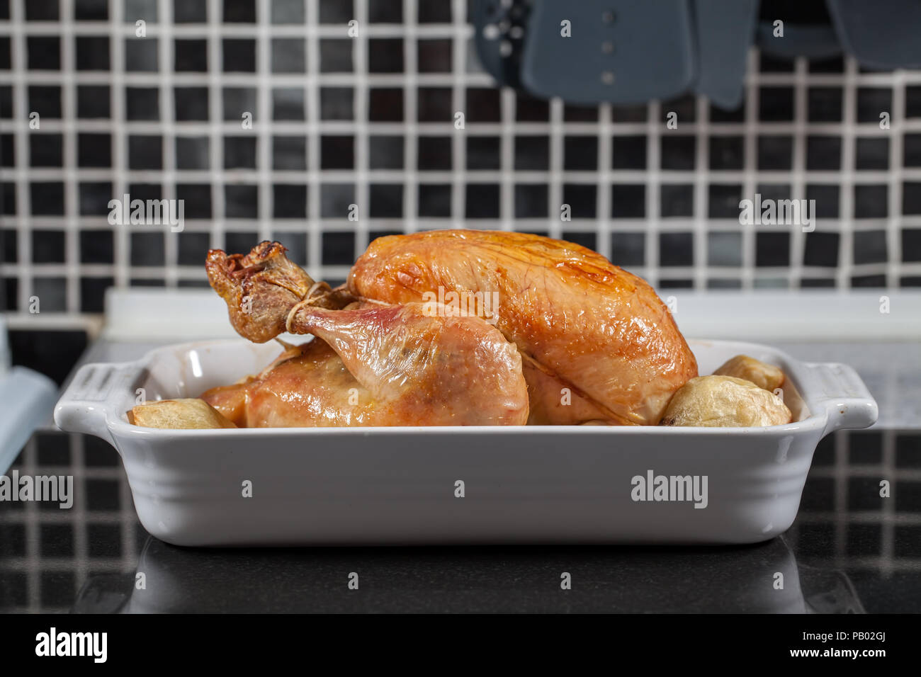 Ensemble four chaud. Poulet rôti cuit Préparé avec des pommes repas dimanche sur le plan de travail de cuisine prêt pour la sculpture et servant pour le dîner. Banque D'Images