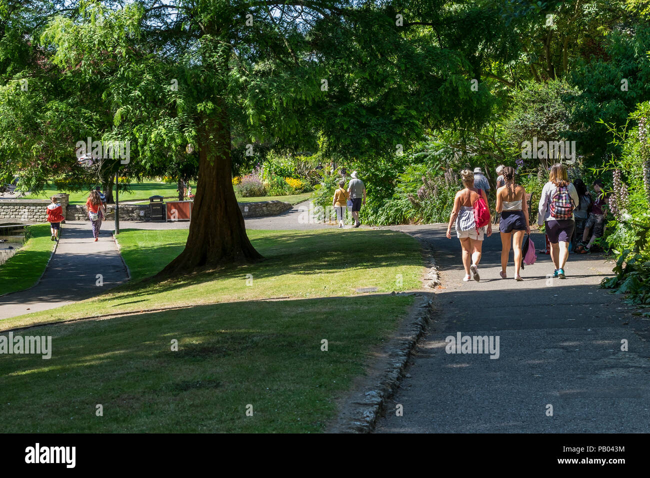 Les gens qui marchent à travers le parc primé Trenance ensoleillée à Newquay en Cornouailles. Banque D'Images