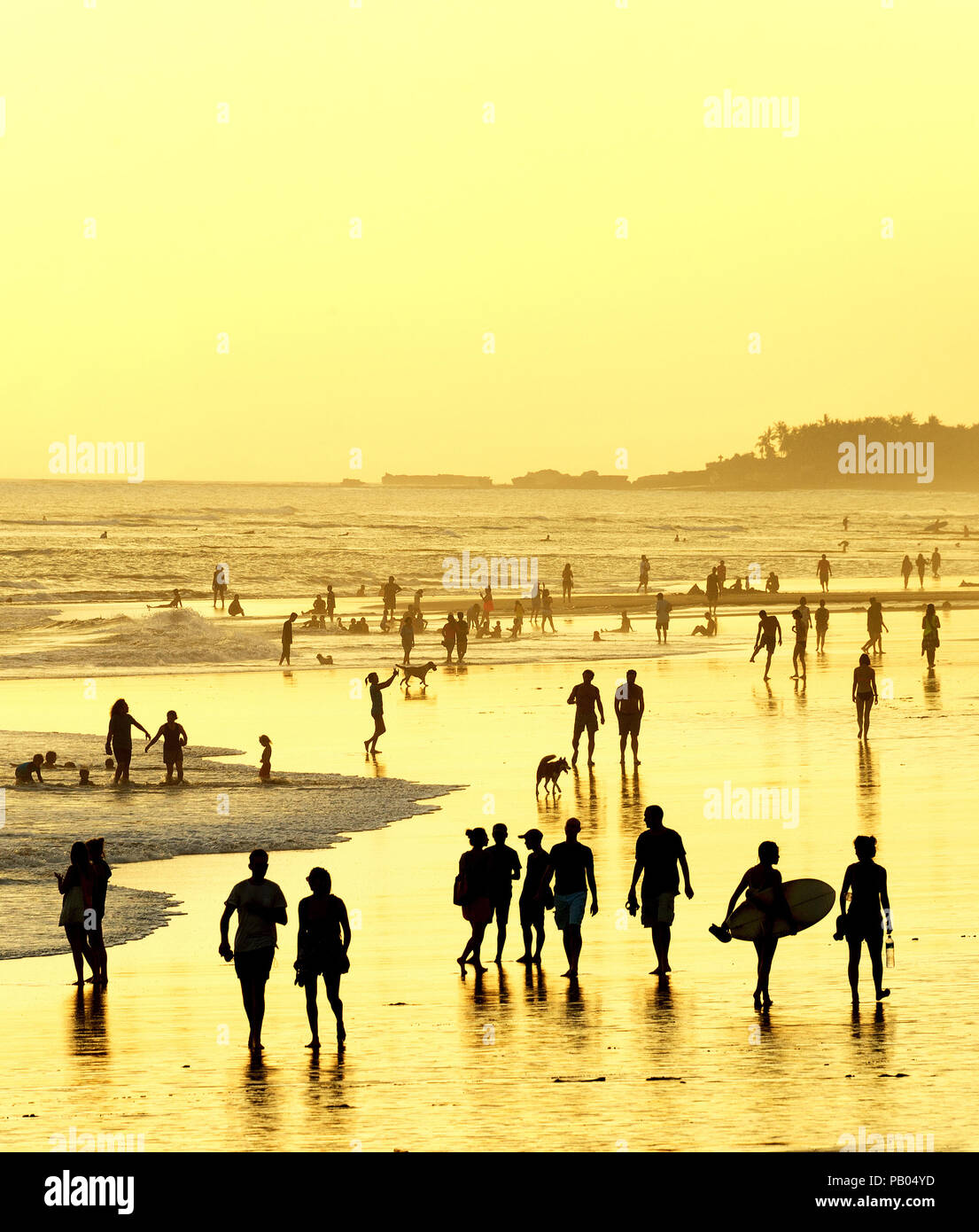 Les gens qui marchent sur la plage sur l'océan au coucher du soleil. L'île de Bali, Indonésie Banque D'Images
