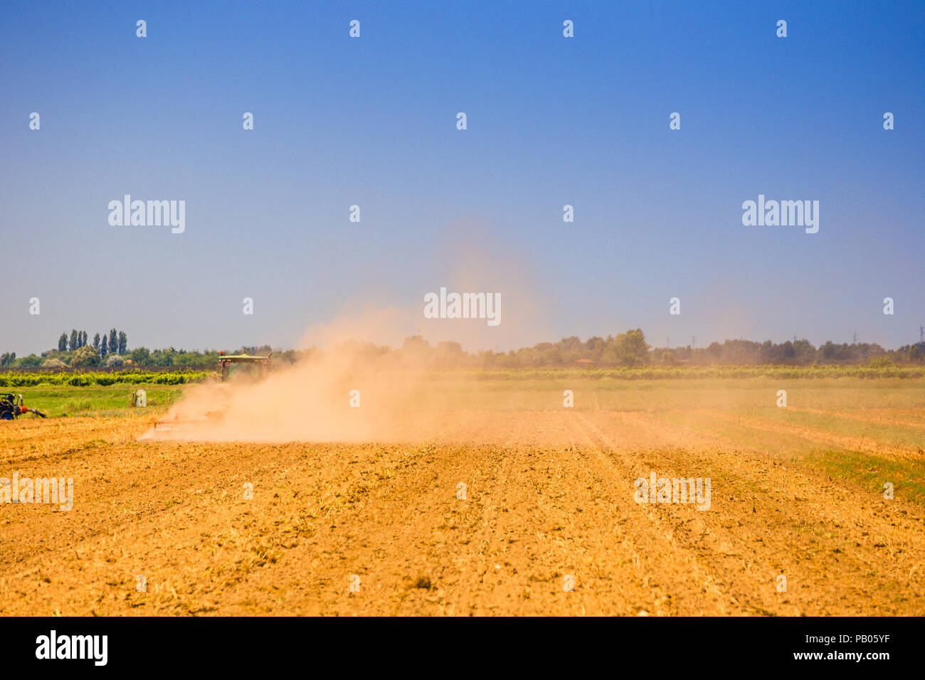 Le tracteur est à labourer le champ dans un nuage de poussière dans un jour d'été torride Banque D'Images
