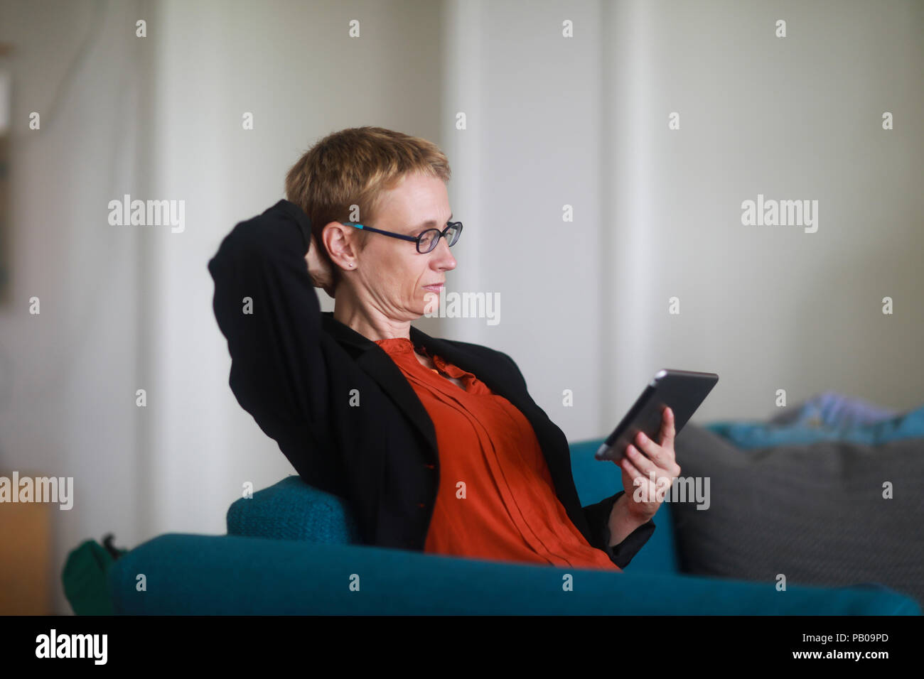 Femme assise sur un canapé à l'aide d'une tablette numérique Banque D'Images