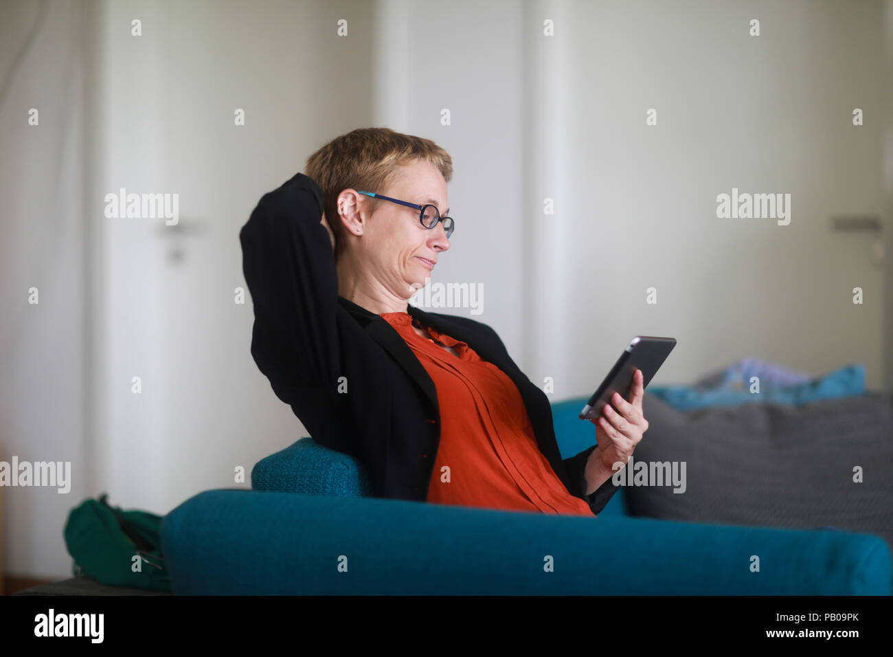 Femme assise sur un canapé à l'aide d'une tablette numérique Banque D'Images
