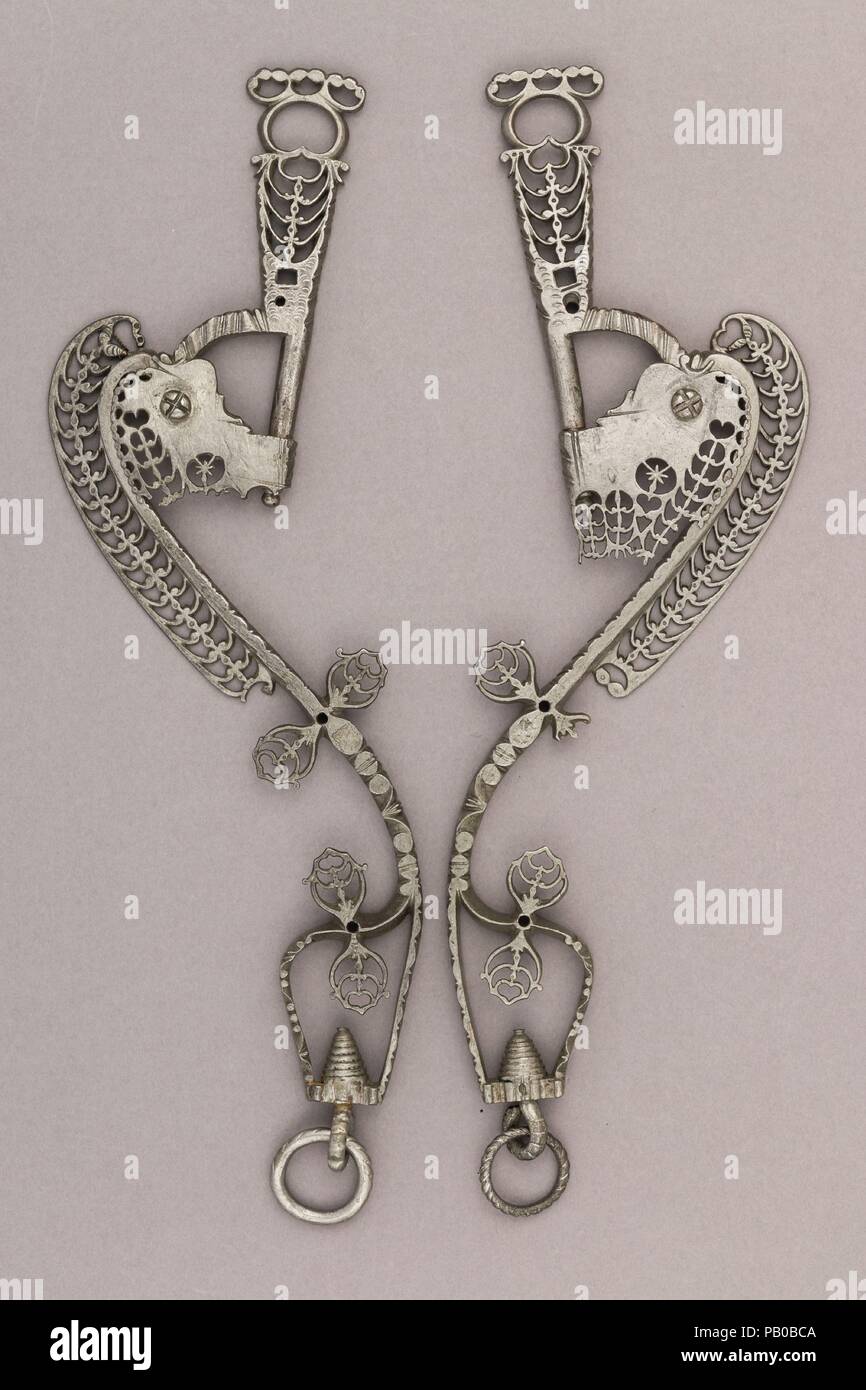 Cheekpieces d'une bordure peu. Culture : l'allemand, Munich. Dimensions : H. de chaque dans 13. (33 cm) ; W. de chaque 4 1/4 in. (10,8 cm) ; WT. 1 lb. 7.8 oz. (674,7 g). Date : le 17e siècle. Probablement utilisé pour l'équitation de loisirs ou de dressage, ce bit, dont l'embouchure est manquant, est entièrement orné de Percé et ciselé motifs géométriques et végétaux, typique de la décoration utilisée par les éperons dans le sud-est de l'Allemagne au 16ème et 17ème siècles. Malgré leur nom, les éperons étaient non seulement fait, mais aussi du petit matériel équestre comme bits, étriers, muselières, cavessons ou curry-comb Banque D'Images