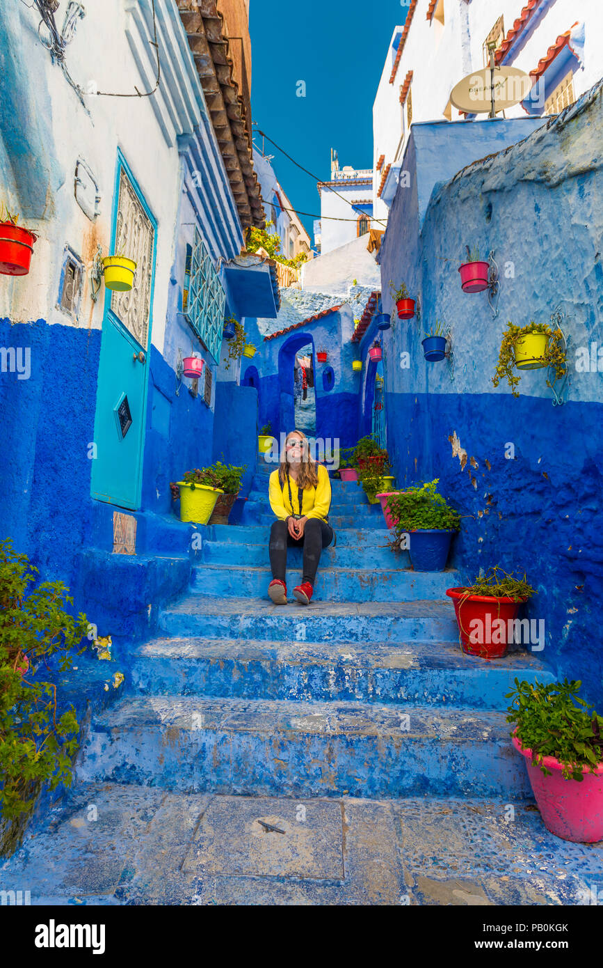 Jeune femme dans la vieille ville se trouve sur un escalier, murs de maison bleue, Médina de Chefchaouen, Chaouen, Tangier-Tétouan Banque D'Images