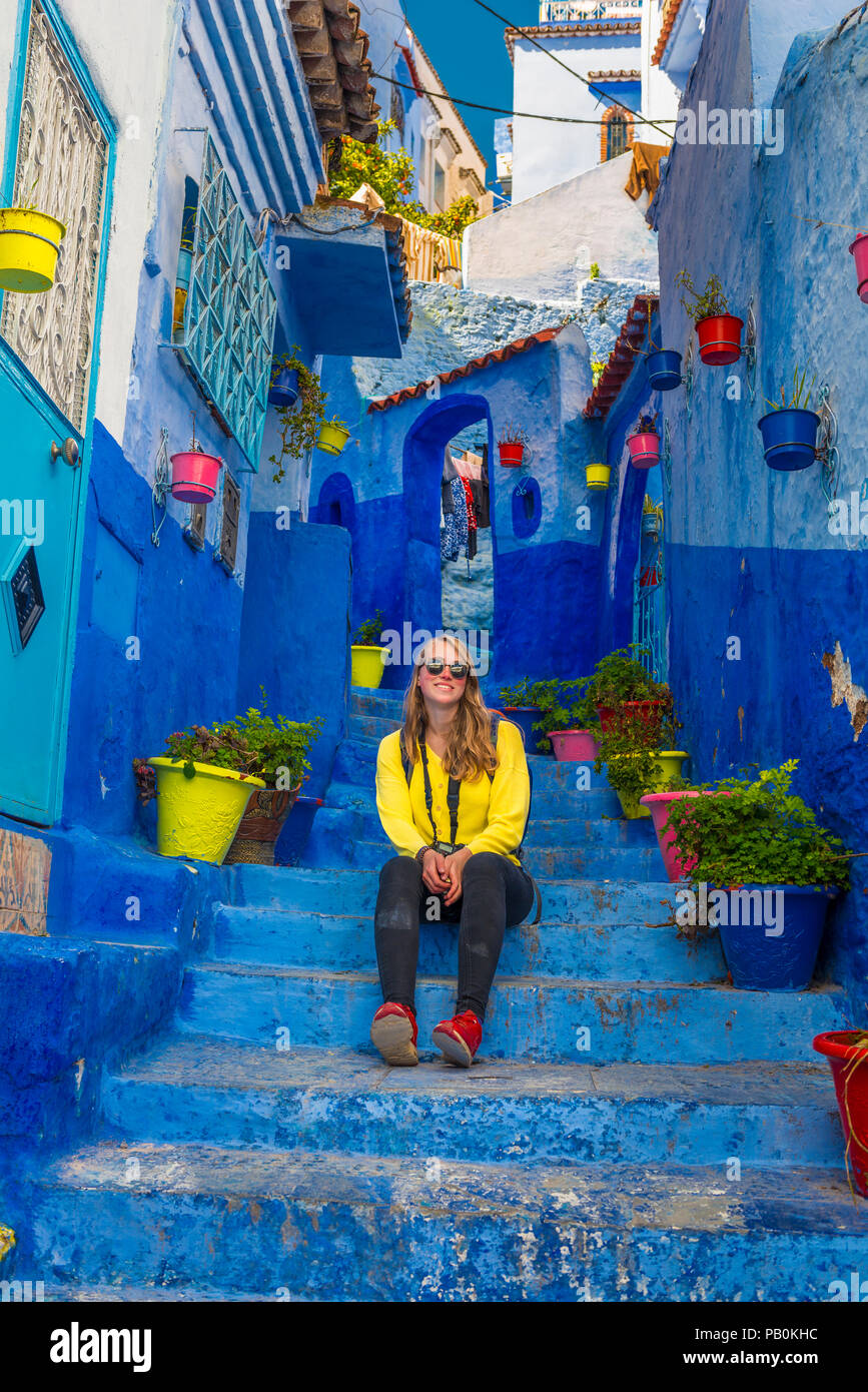 Jeune femme dans la vieille ville se trouve sur un escalier, murs de maison bleue, Médina de Chefchaouen, Chaouen, Tangier-Tétouan Banque D'Images