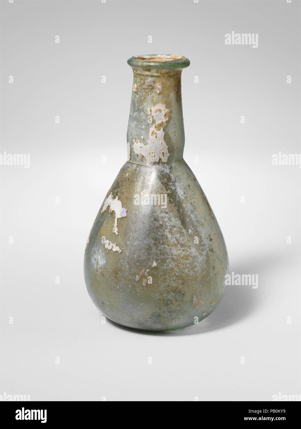Flacon de parfum en verre. Culture : Roman. Dimensions : hors tout : 4 1/4 x 2 7/16 x 1 in. (10,8 x 6,2 x 2,5 cm). Date : 1er et 2e siècle de notre ère. Lumière pâle Translucide bleu. De plus, Rim, et dans, aplati sur le dessus ; le cou en forme d'entonnoir avec côtés bombés légèrement remanié et tiret autour de base ; corps ovoïde ; fond Glénat. Complète, mais se fissurer autour du cou juste au-dessous de la jante et d'autres fissures verticales dans le cou et le corps, d'autres bulles piqûre ; ternissement, s'évanouir, l'iridescence et de parcelles de l'altération d'un blanc crémeux sur l'extérieur, l'incrustation et l'altération du sol blanchâtre sur l'intérieur. Musée : Metropolita Banque D'Images