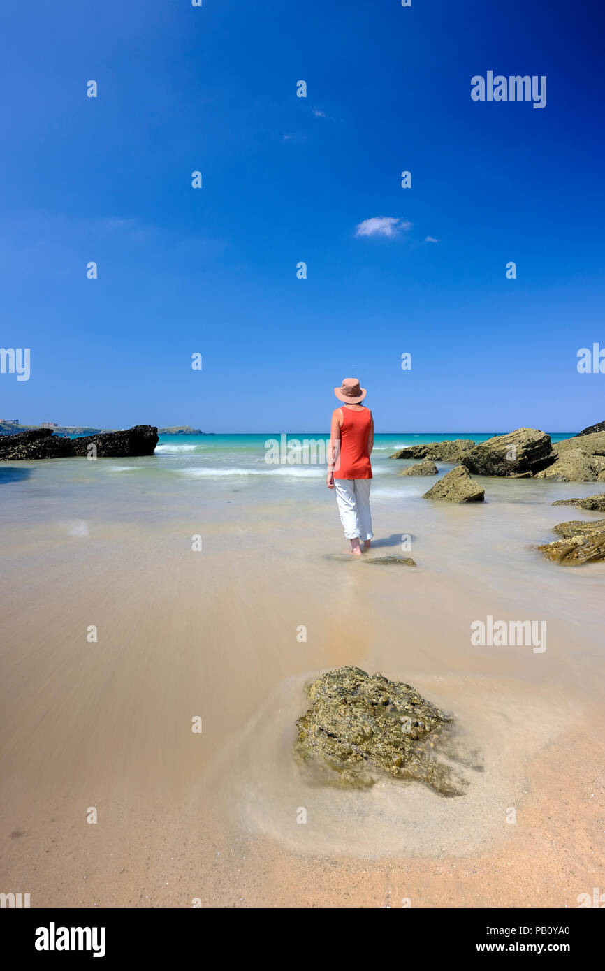 Femme debout dans l'eau peu profonde sur une belle plage à Cornwall Banque D'Images