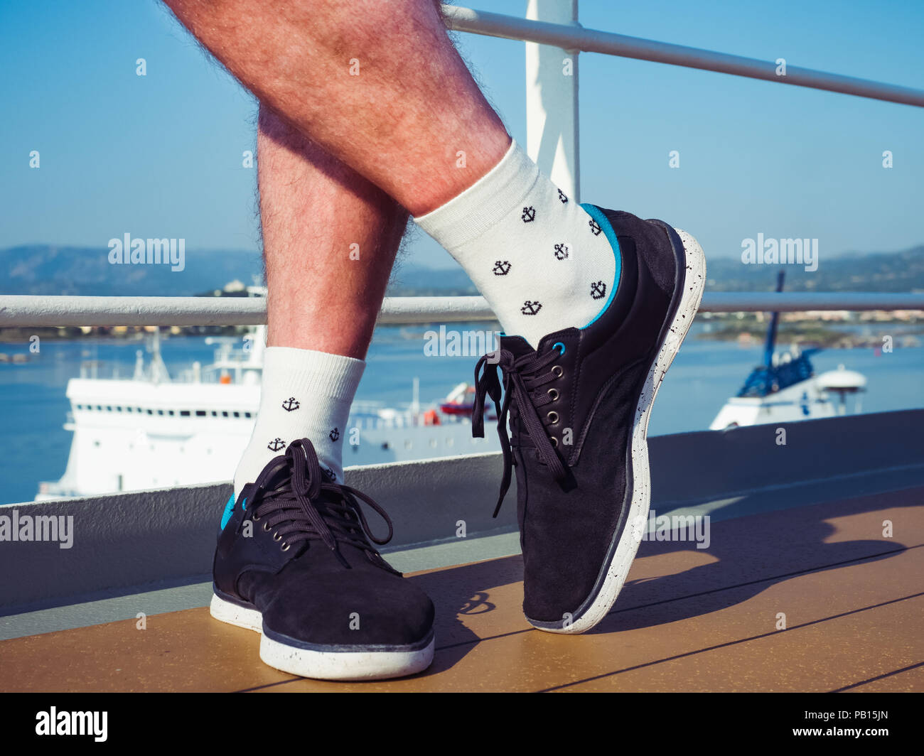 Men's pieds dans les chaussures de sport et de chaussettes blanches avec un  motif de la mer sous la forme d'ancres sur le pont d'un bateau de croisière  dans le contexte de