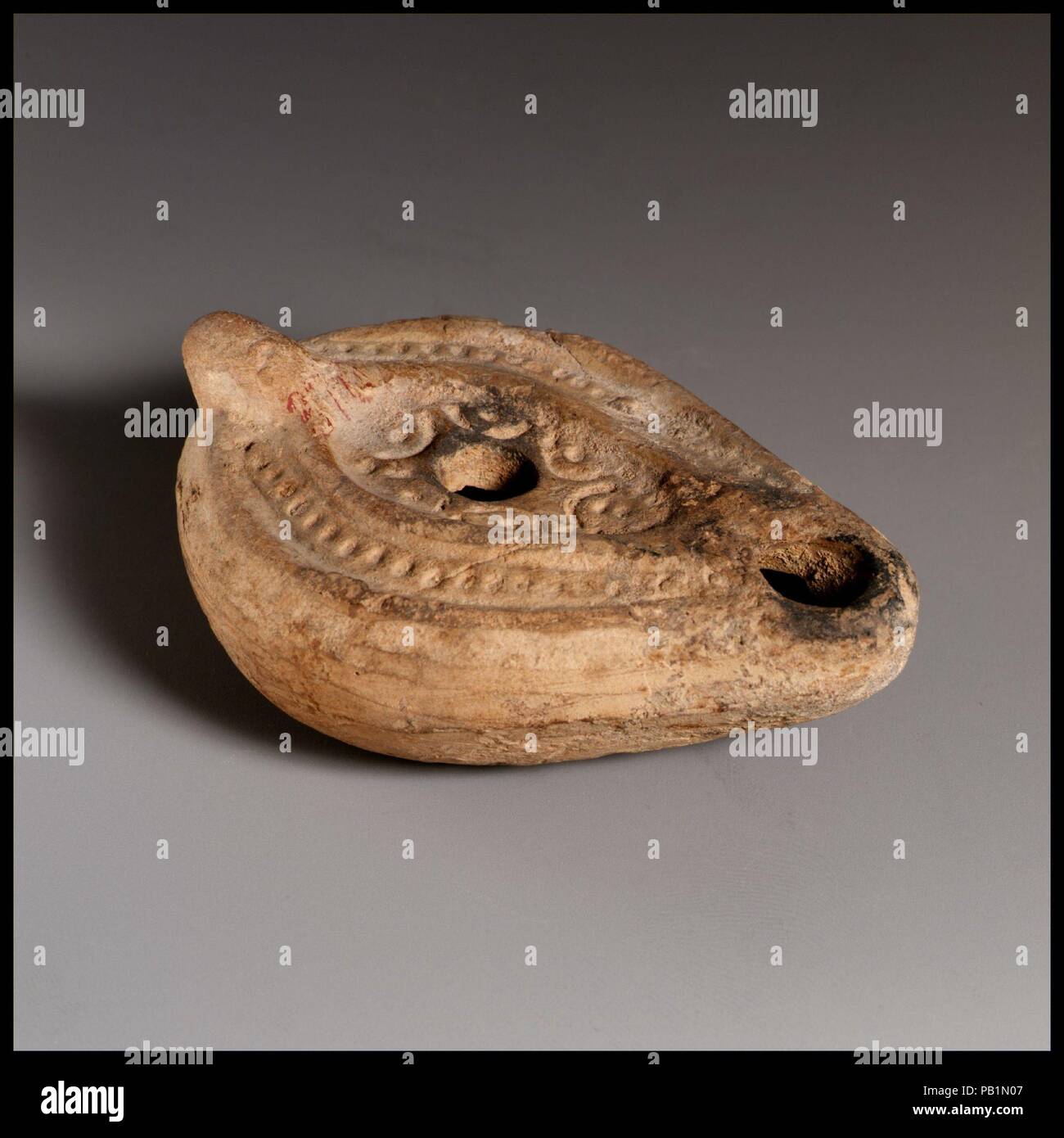 Lampe à huile en terre cuite. Culture : Roman. Dimensions : hors tout : 1 1/8 x 2 3/4 in. (2,9 x 7 cm). Date : le 3e siècle de notre ère. Faites-moule, avec poignée non percée. Entouré d'un disque ovale soulevées ligne qui va vers la mèche dans le trou ;, une étoile et croissant, avec des cercles ou des carrés intercalés. Sur l'épaule, un étroit nband de lignes, avec une autre ligne soulevées autour du bord. Undefined base. Intacts. Musée : Metropolitan Museum of Art, New York, USA. Banque D'Images