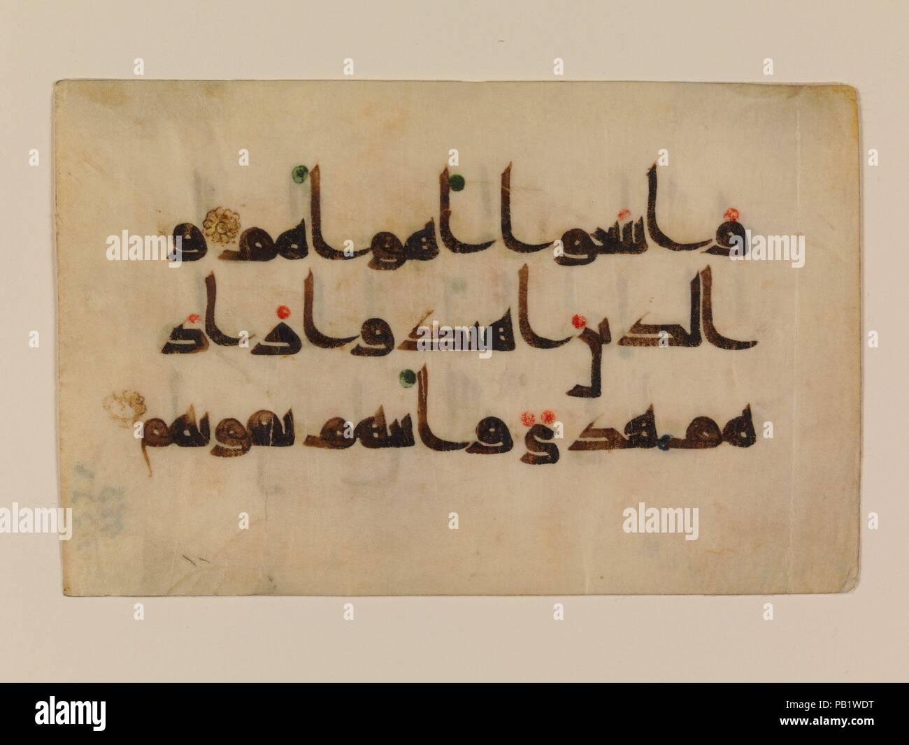 Folio à partir d'un Coran manuscrit. Dimensions : H. 3 5/16 in. (8,4 cm) O. 5 1/16 in. (12,9 cm). Date : 9ème-début 10ème siècle. Comme beaucoup de Coran folios, ce folio est écrit en parchemin à l'encre noire à l'aide d'un stylo. reed nibbed De l'horizontale, arrondi des lettres qu'on voit ici sont caractéristiques de Qur'ans coufique sur parchemin, et sont pensées pour être une réponse à la page format rectangulaire. Le script angulaire est animée par la rondeur de plusieurs lettres qui ressemblent à de gros points noirs, leurs espaces intérieurs réduits à de petits cercles. Le rouge et les points verts indiquent la voyelle marques. Musée : Banque D'Images