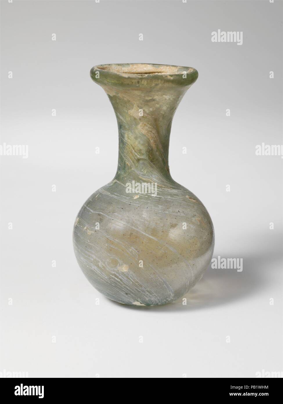 Flacon en verre. Culture : Roman. Dimensions : H. 3 1/2 in. (8,9 cm). Date : 3e et 4e siècle de notre ère. Bleu pâle translucide vert. Jante tubulaire éversée, repliées et dans la bouche en forme d'entonnoir ; ; ; cou cylindrique concave ; corps globulaire fond épais avec de petits coup de pied central et pontil cicatrice. Intacts ; certaines plus grandes bulles, piqûre et stries de soufflage ; piqûres, ternissement, blanchâtre, d'altération et irisés. Musée : Metropolitan Museum of Art, New York, USA. Banque D'Images