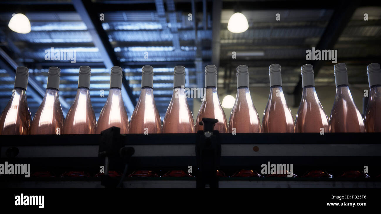 Des bouteilles de vin rosé sur le tapis roulant. Banque D'Images