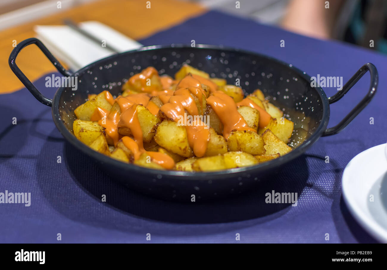Patatas bravas (pommes de terre) avec l'espagnol de couleur orange épicé (salsa brava brava sauce) ou alioli (aïoli). Patatas Bravas est un classique et très po Banque D'Images