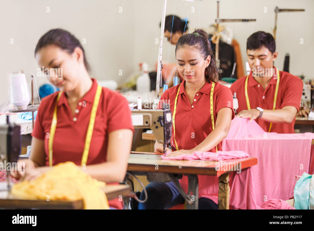 Les travailleurs asiatiques en usine de confection de coudre avec couture industrielle m Banque D'Images