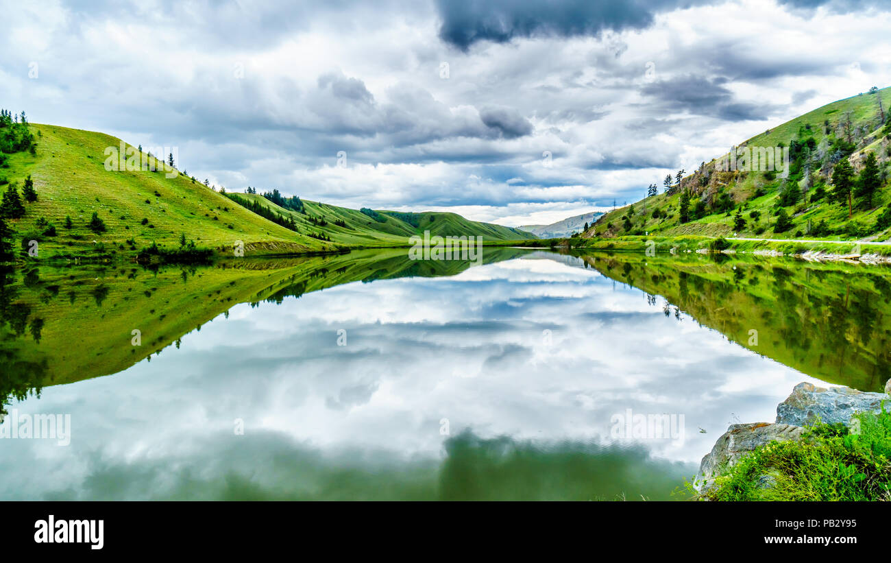 Les nuages sombres et les montagnes environnantes se reflétant dans l'eau du lac Trapp, le long de l'autoroute 5A entre Kamloops et Merritt dans belle BC Canada Banque D'Images