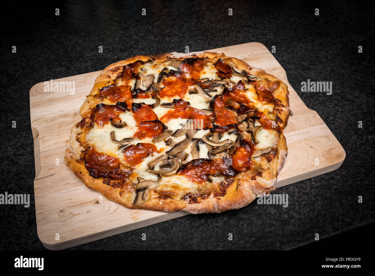 Maison faits à la main et aux champignons pizza au chorizo sur planche de bois du four Banque D'Images