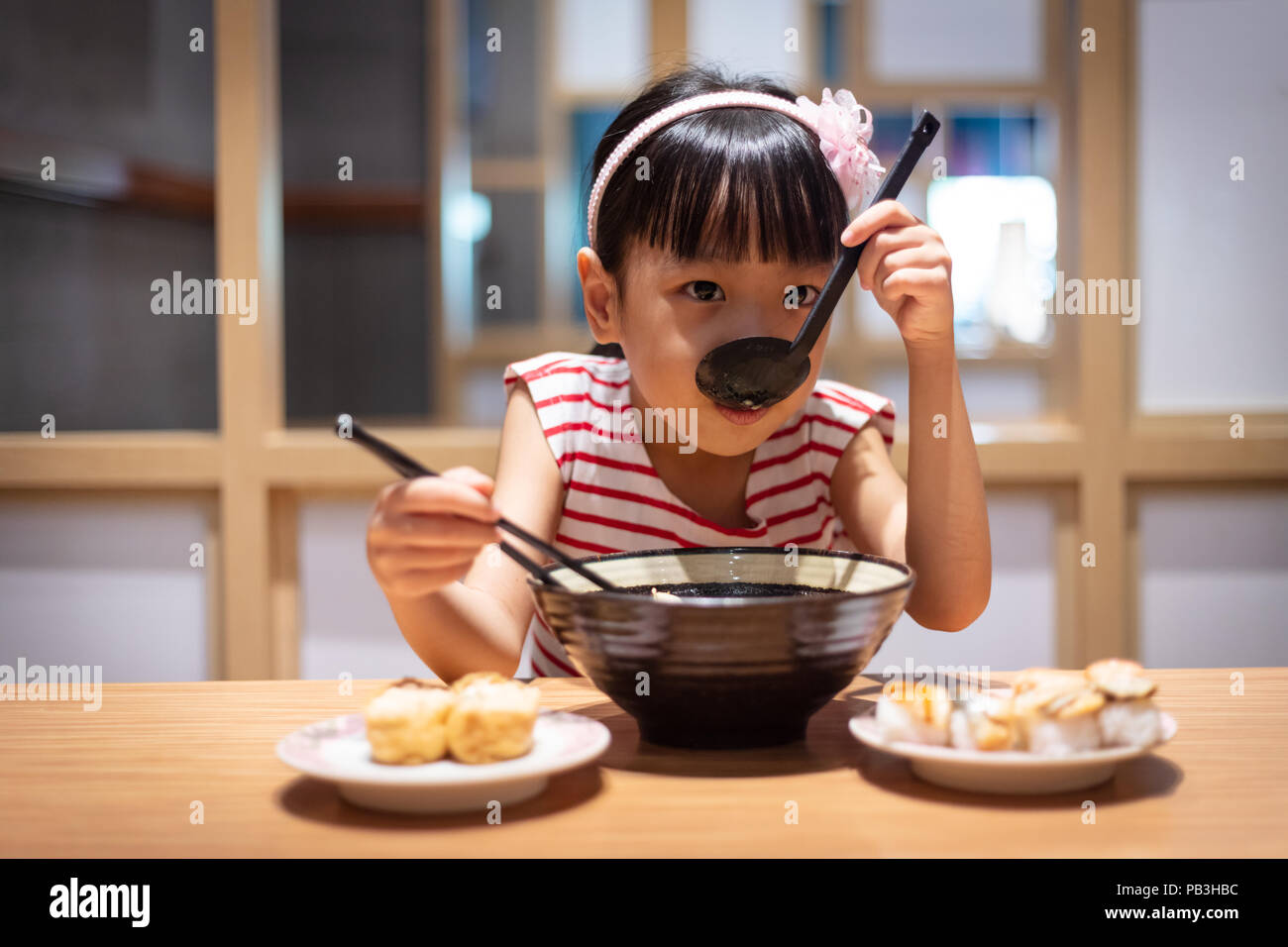 Peu asiatique Chinese girl eating nouilles ramen à un restaurant japonais Banque D'Images