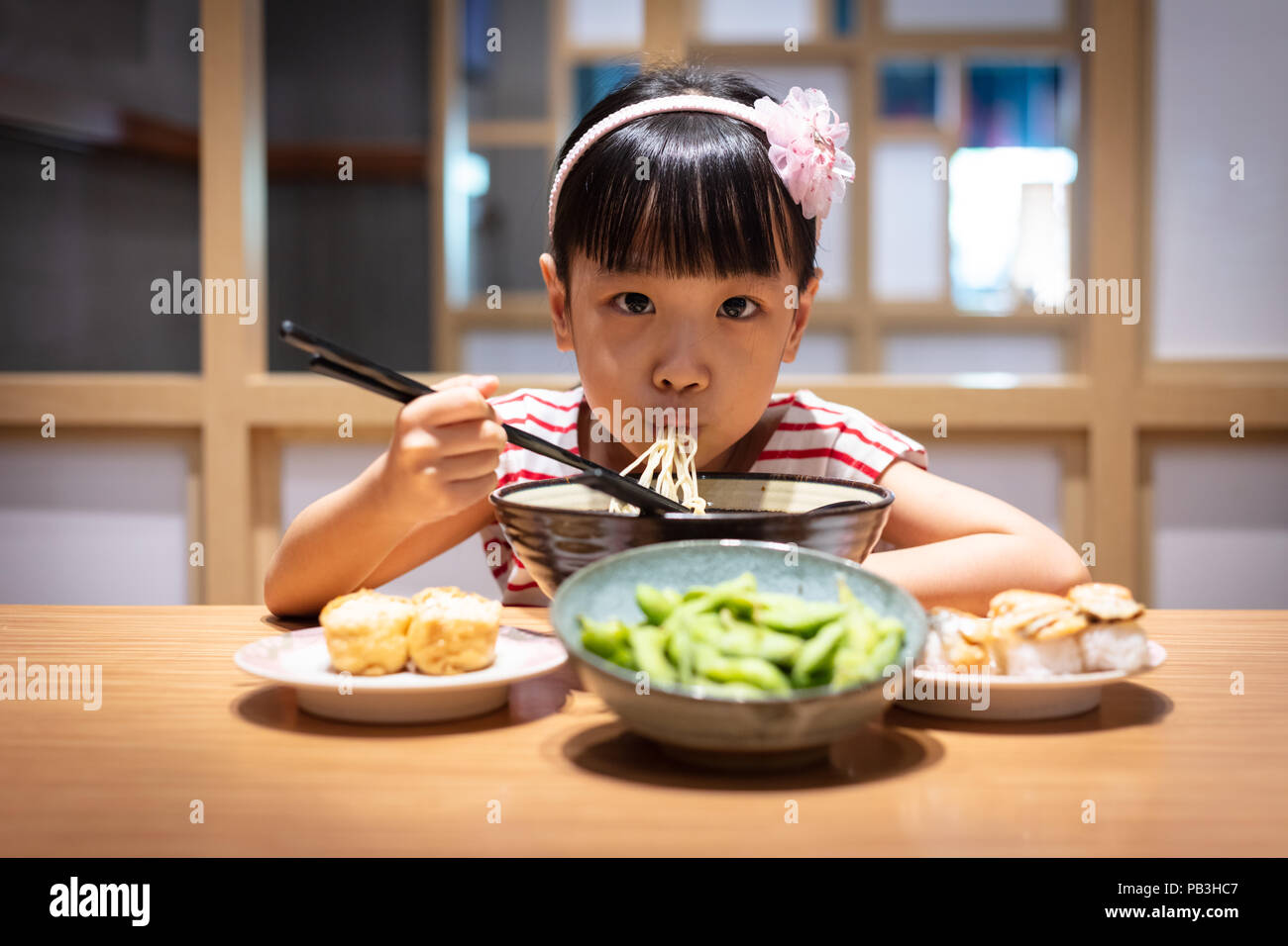Peu asiatique Chinese girl eating nouilles ramen à un restaurant japonais Banque D'Images
