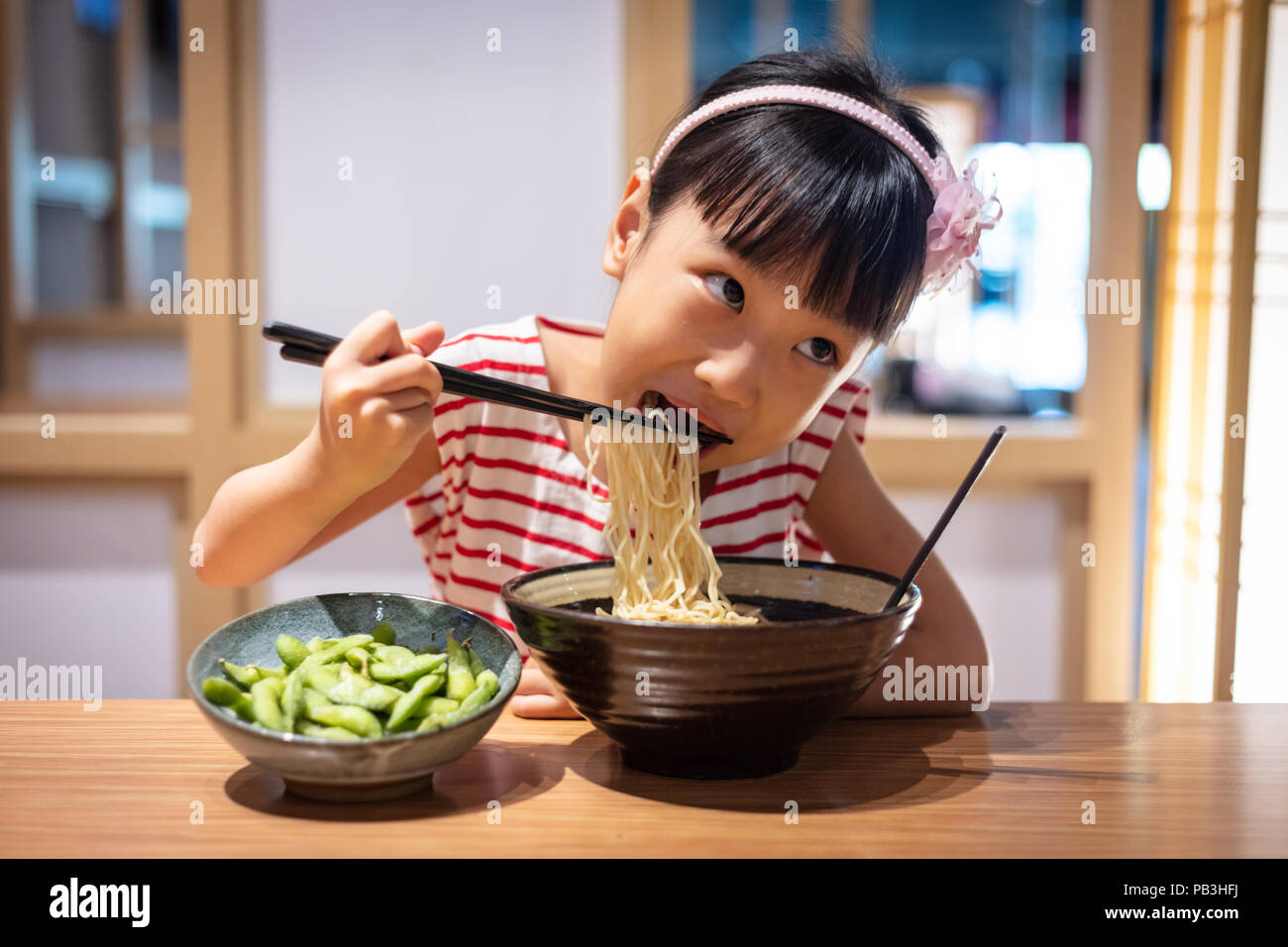Peu asiatique Chinese girl eating nouilles ramen à un restaurant japonais Banque D'Images