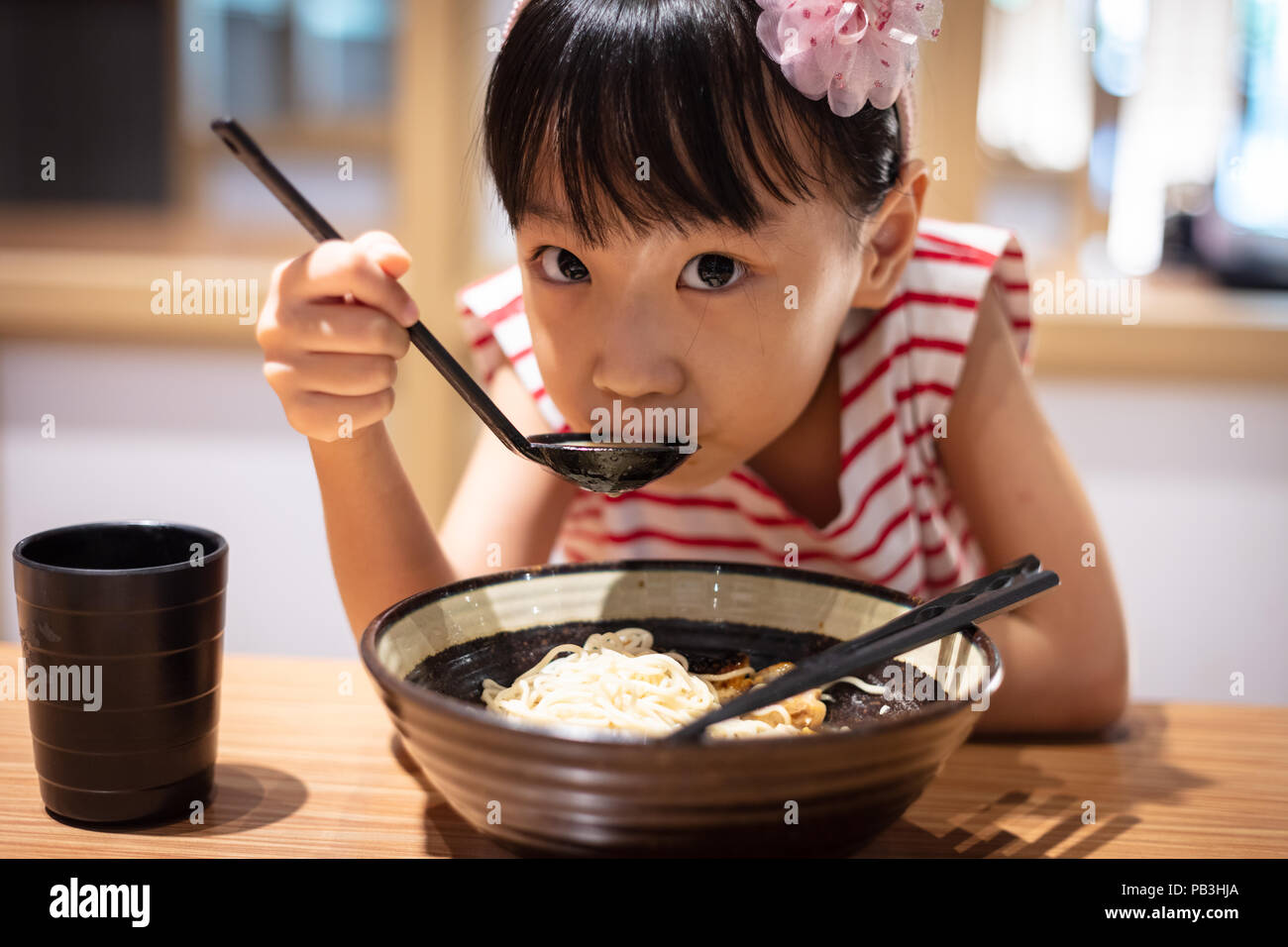 Peu asiatique Chinese girl eating nouilles ramen à un restaurant japonais Banque D'Images