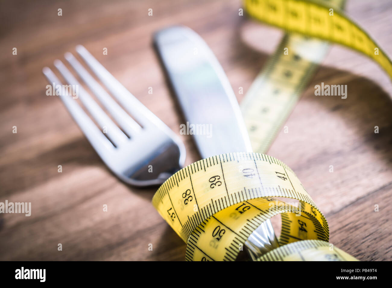 Fourchette et couteau macro de l'Argenterie attachées ensemble avec un ruban à mesurer sur une table - Perdre du poids Concept Banque D'Images