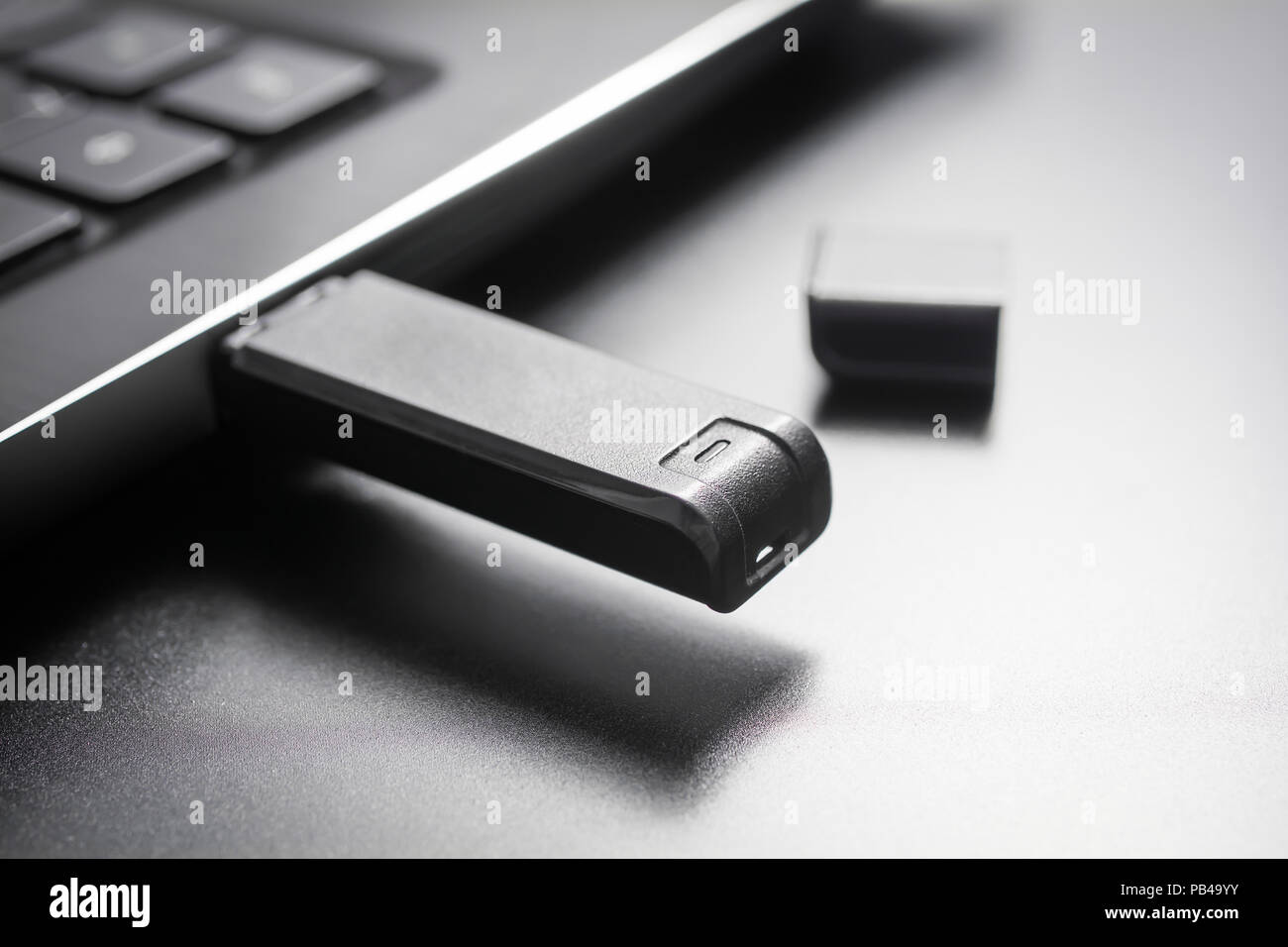 Macro d'une bâton de mémoire CLÉ USB branché sur le port USB d'un ordinateur portable noir, Side View Banque D'Images