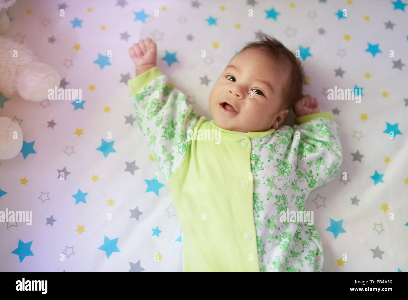 Bibelots little baby girl laying on bed et chercher à huis clos Banque D'Images