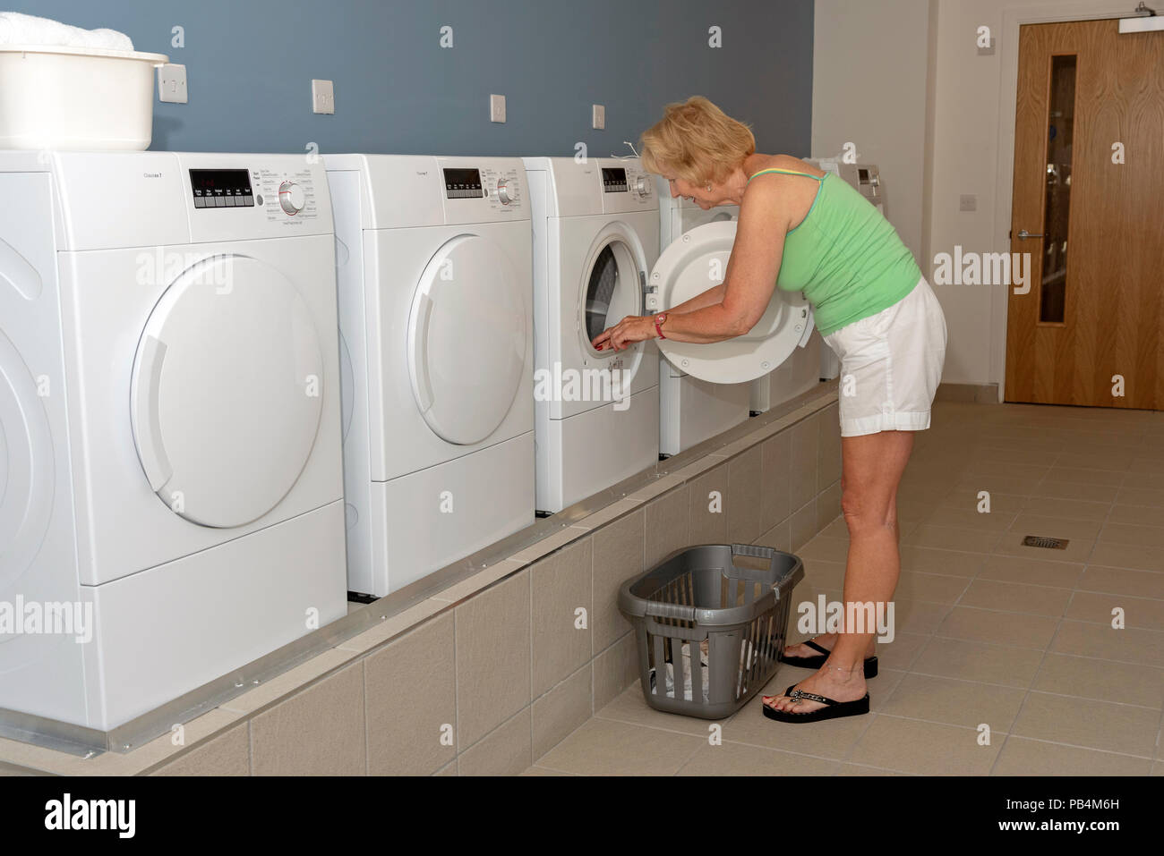 Femme à l'aide d'un sèche linge dans une buanderie. Banque D'Images