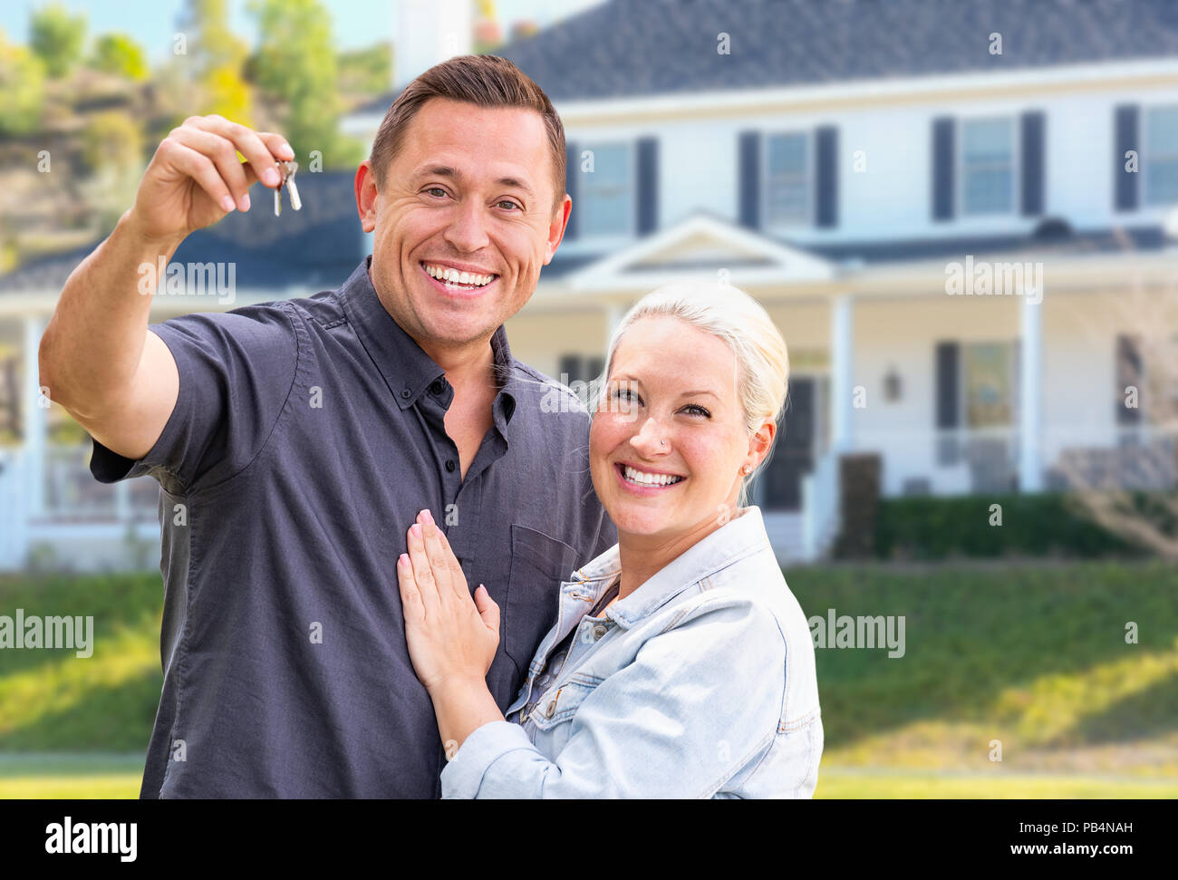 Jeunes adultes en couple avec clés de maison en face de la belle maison. Banque D'Images