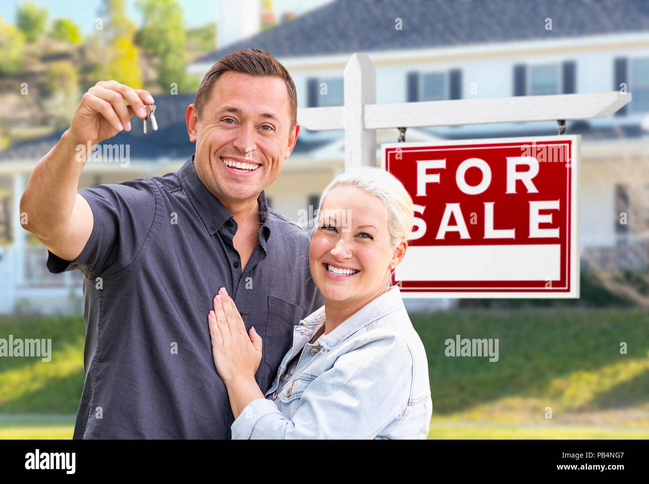 Jeunes adultes en couple avec clés de maison en face de la maison et achat immobilier signe. Banque D'Images