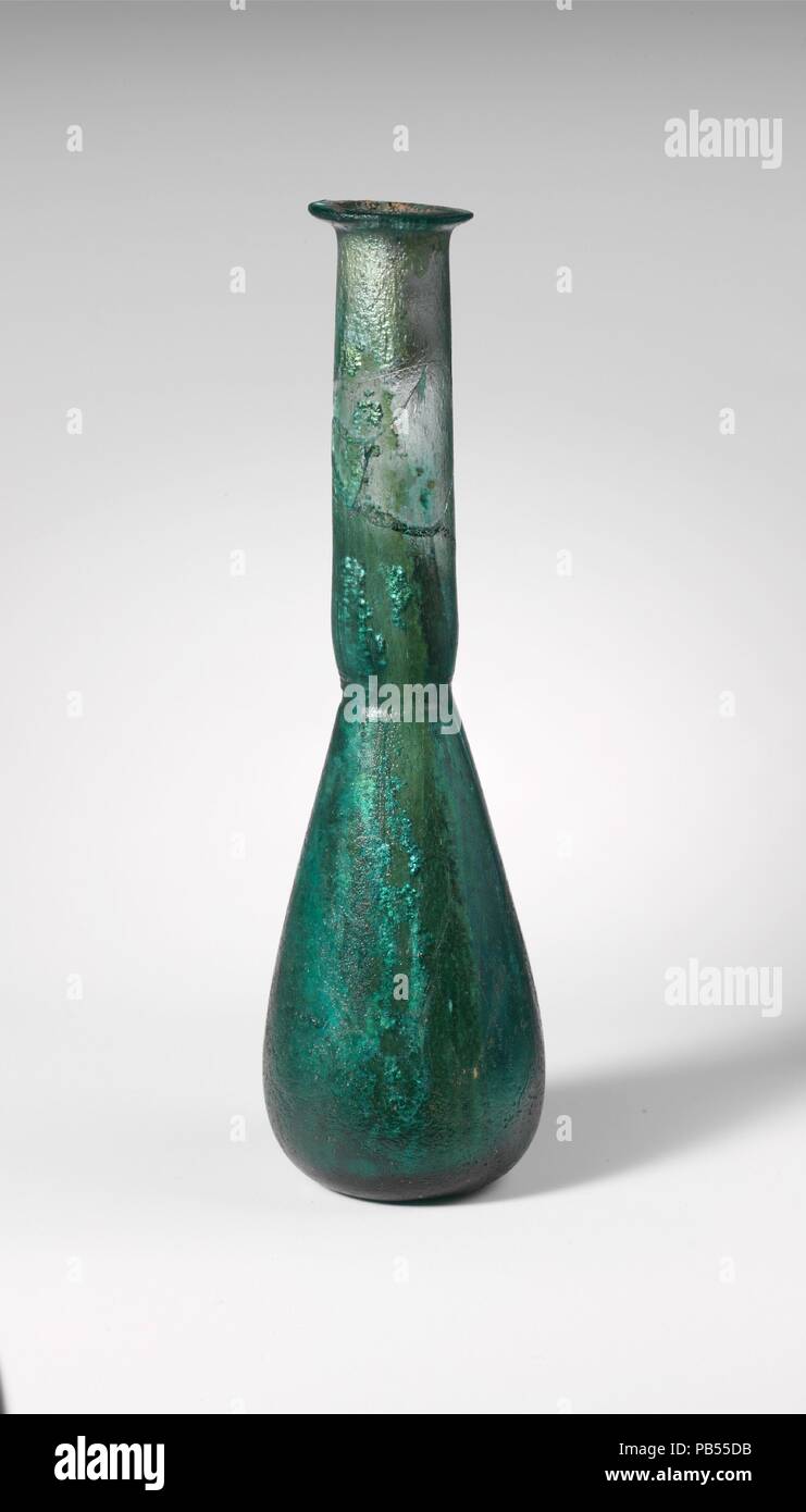 Flacon de parfum en verre. Culture : Roman. Dimensions : hors tout : 7 1/8 x 2 1/8 x 1 1/8 in. (18,1 x 5,4 x 2,9 cm). Date : 2ème-3ème siècle de notre ère. Bleu translucide vert. Rebord plié sur et dans, repassé à plat sur la surface supérieure et formant une légère constriction de la bouche ; grand cou cylindrique avec tiret outillage autour de base ; corps conique, légèrement plus de la moitié de la hauteur totale ; épaisses, aplatie en bas avec pontil cicatrice. Cou cassé et réparé, avec un grand trou, mais RIM et le corps complet ; de bulles ; des piqûres sur l'extérieur, l'incrustation, l'altération du sol noir, brillant et iridescen Banque D'Images