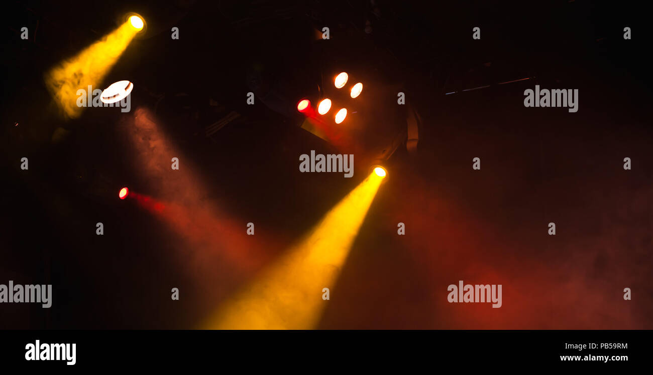 Des spots rouges et jaunes avec des poutres apparentes en fumée sur fond sombre, stade moderne d'équipement d'éclairage Banque D'Images