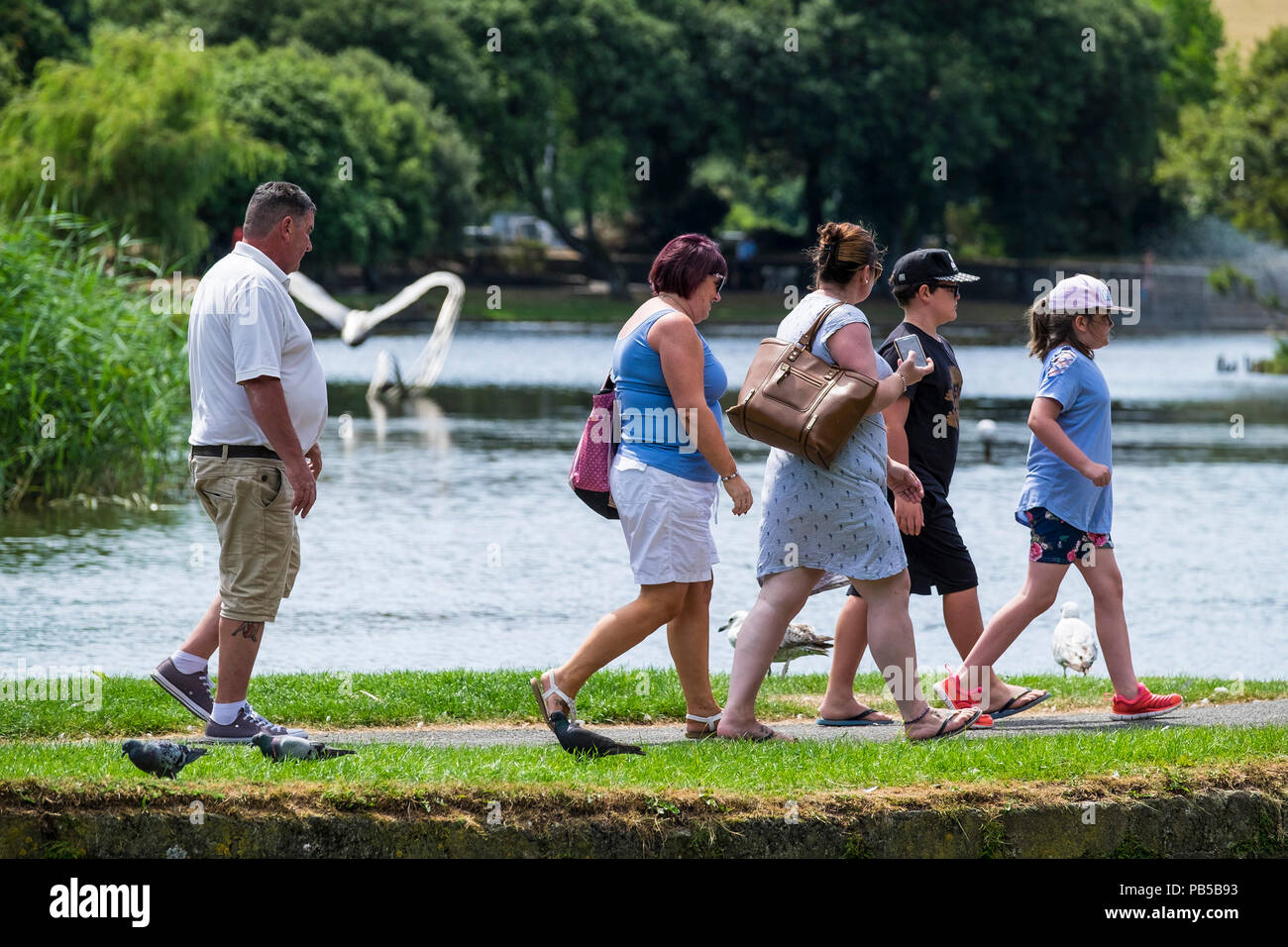 Une famille de vacanciers britanniques à marcher le long de la rive d'un lac dans la région de jardin Trenance Newquay Cornwall. Banque D'Images