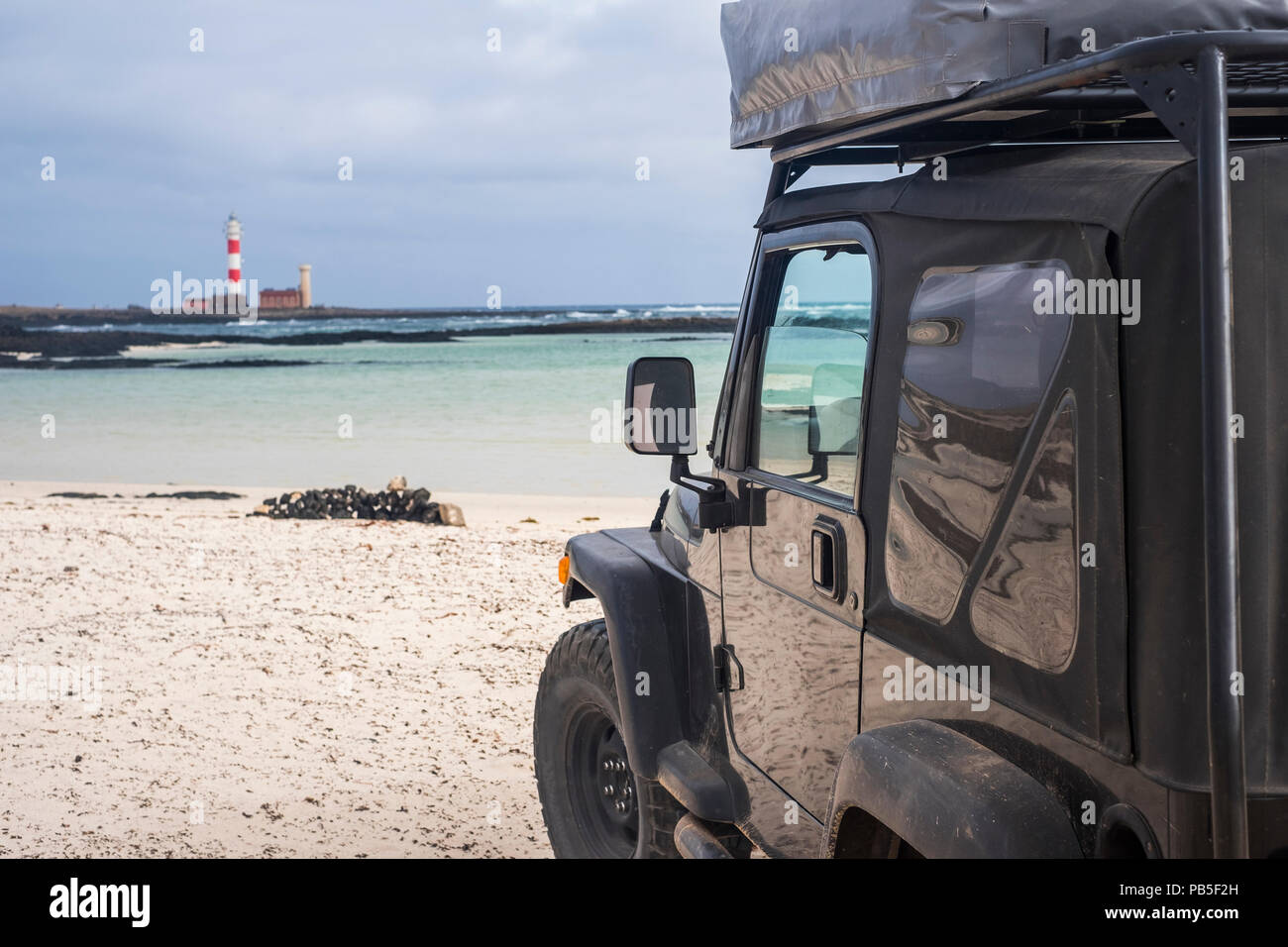 Grand véhicule hors route de haut noir voiture solide explorer la plage et regarder le phare en arrière-plan. autre façon de voyager et de style de fo Banque D'Images
