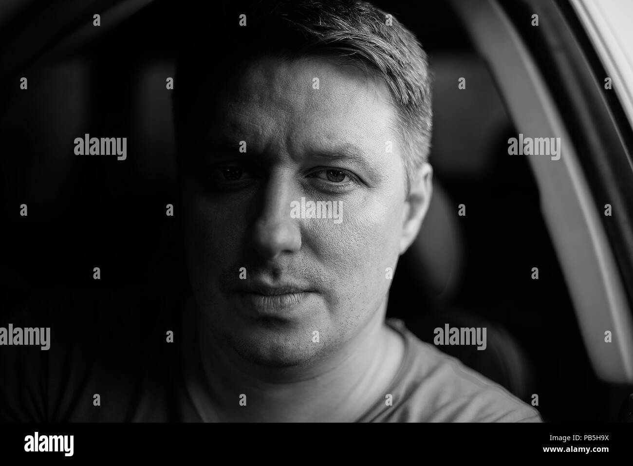 Portrait d'un homme dans une voiture close-up dans des tons noir et blanc. Photo monochrome. Banque D'Images