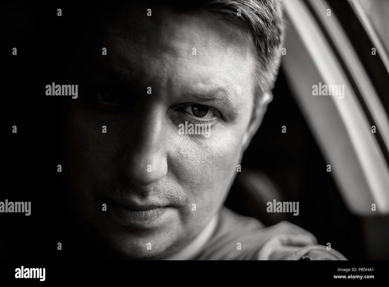 Portrait d'un homme dans une voiture close-up dans des tons noir et blanc. Photo monochrome. Banque D'Images