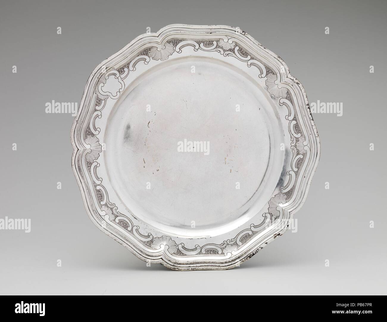 La plaque. Culture : l'anglais, Toulouse. Dimensions : Diamètre : 9 3/4 in., 18.134oz. (24,8 cm, 514.1g). Bouilloire : Louis Landes (master ca. 1770, 1789 active). Date : 1774. Bols couverts comme cela était connu en France comme ecuelles, et étaient destinées à servir le bouillon chaud ou de la soupe. On a communément bouillon servi le matin dans la chambre au cours de la toilette, le lavage rituel élaboré et d'un dressing. Le couvercle du bol conservé le contenu chaud, et le bouillon peut être sirotée dans le bol en utilisant les deux poignées, tandis que pain reposait sur le stand. Ce bassin et sont décorées avec le plus commun o Banque D'Images