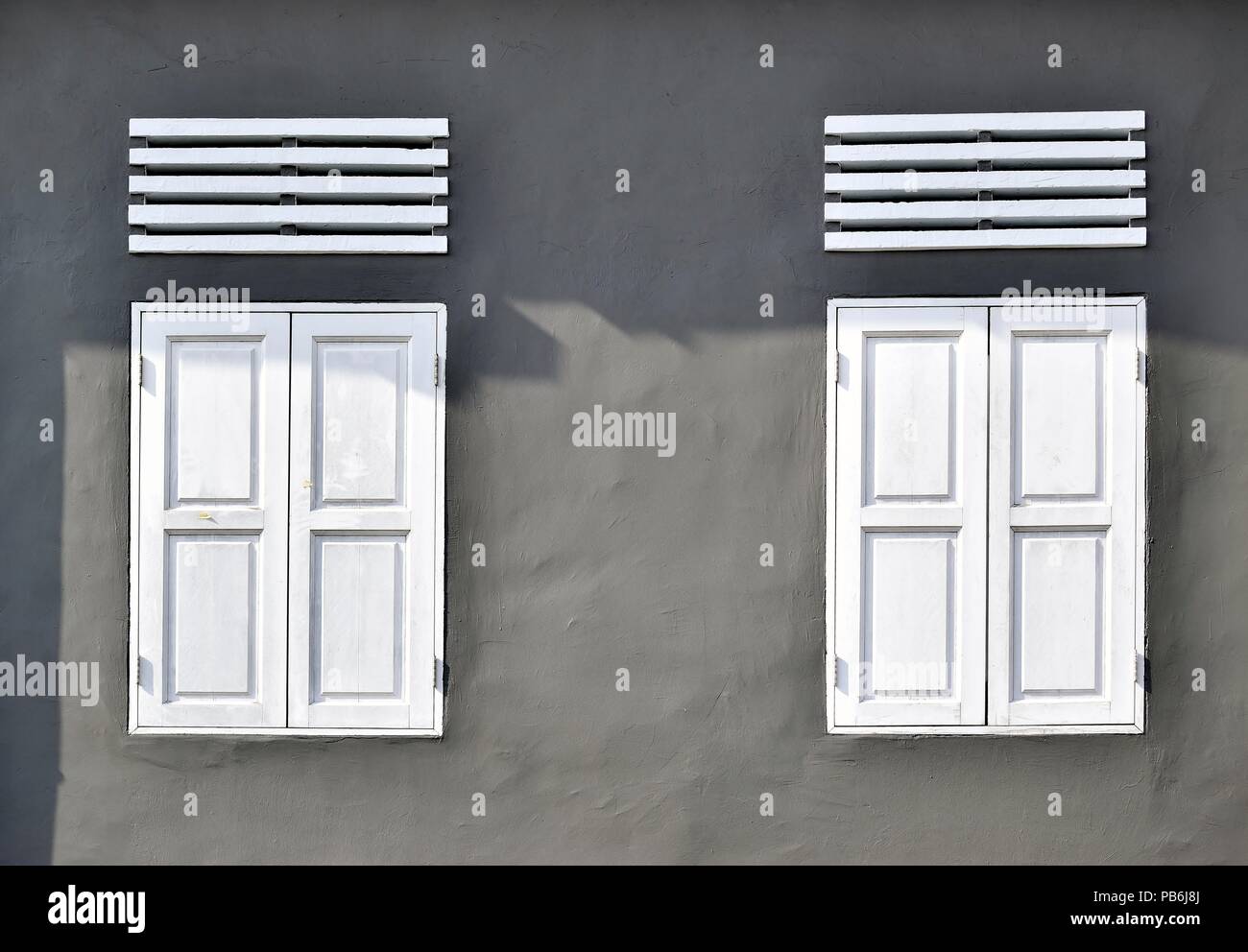 Vue avant Vue de l'antique blanc fenêtres avec volets en bois gris sur le mur d'une maison à Singapour comme vintage avec espace pour copier. Banque D'Images