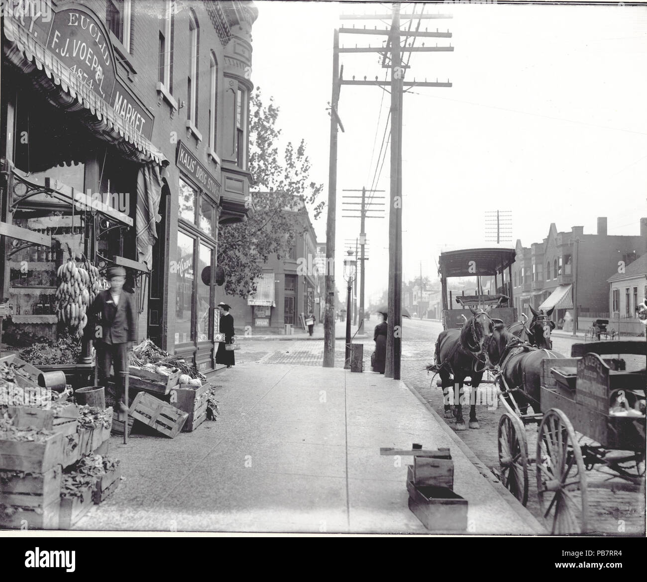 1553 coin sud-est de l'avenue Easton (M.L. King drive) et Euclid Avenue. Un garçon sur pilotis se place en avant de la produire devant la F.J. Voepel Market Banque D'Images