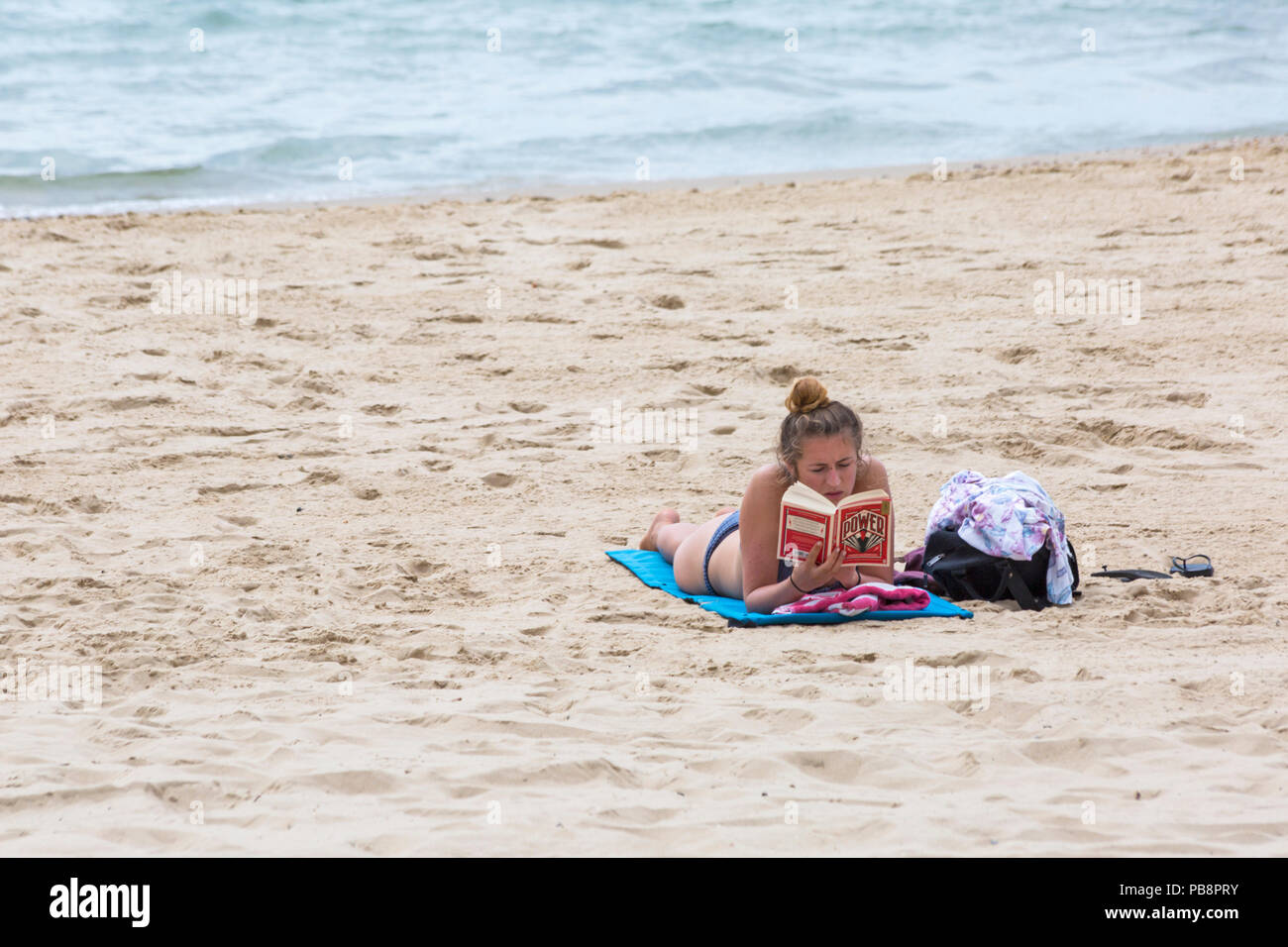 Bournemouth, Dorset, UK. 27 juillet 2018. Météo France : la station de tête Sunseekers à bronzer sur les plages de Bournemouth sur un jour chaud et humide avec quelques nuages. De soleil femme lecture livre - le pouvoir, un roman de science-fiction de 2016 par l'écrivain britannique Naomi Alderman. Credit : Carolyn Jenkins/Alamy Live News Banque D'Images