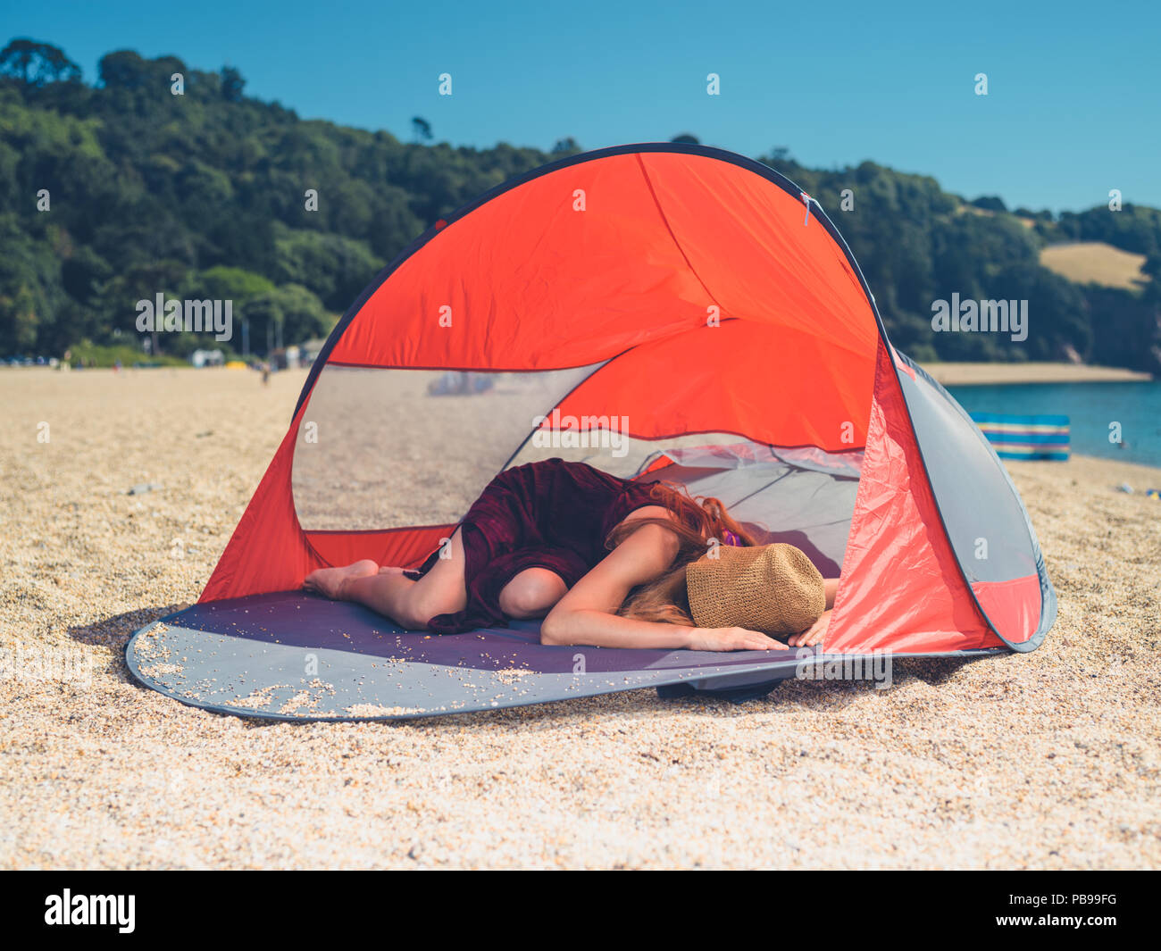 Une jeune femme est en train de dormir dans un abri de plage en été Banque D'Images