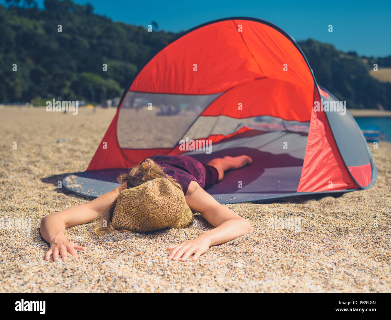 Une jeune femme est en train de dormir dans un abri de plage en été Banque D'Images