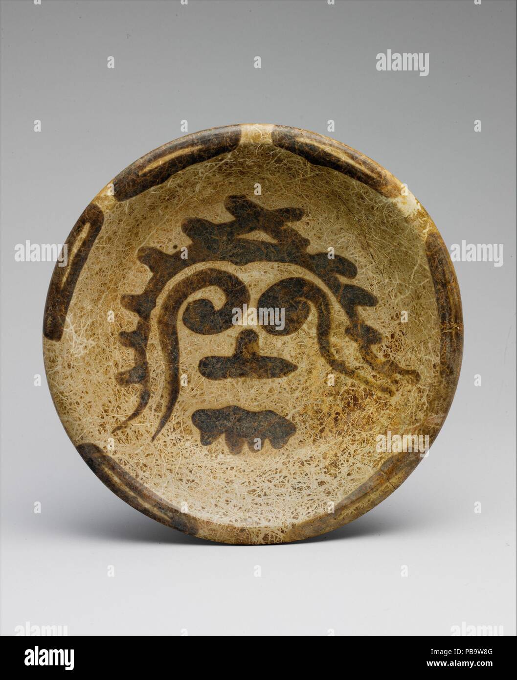 La plaque de tripode. Culture : Maya. Dimensions : H. 2 1/2 x diam. 10 7/8 in. (6,4 x 27,6 cm). Date : 9ème-10ème siècle. Mentionnée par les archéologues comme slateware, ce navire en céramique est une variété qui a été particulièrement populaire dans le nord du Yucatan au cours des siècles autour de la fin du deuxième millénaire après J.C. le slateware de couleurs, allant du beige pâle à gris-blancs doux, sont en contraste marqué avec les céramiques polychromes mayas dynamique d'autrefois. Comme dans cet exemple, la décoration est souvent limitée. L'image qui orne la surface interne de cette plaque rappelle la Mesoamerican trépied Banque D'Images
