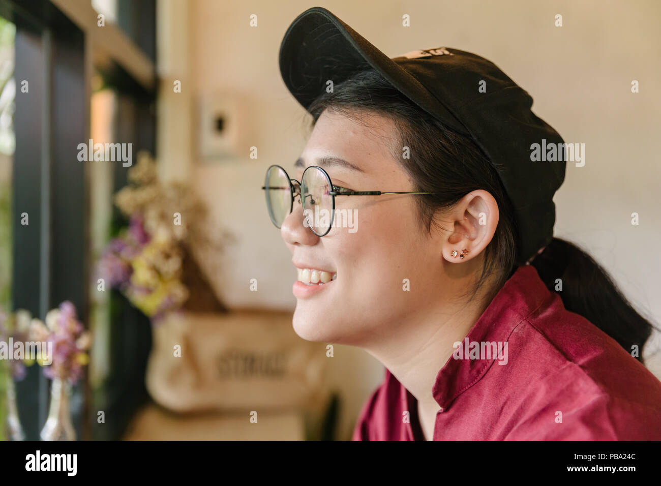 Cute Asian teen graisse sourire avec sourire et lunettes à la recherche de windows Banque D'Images
