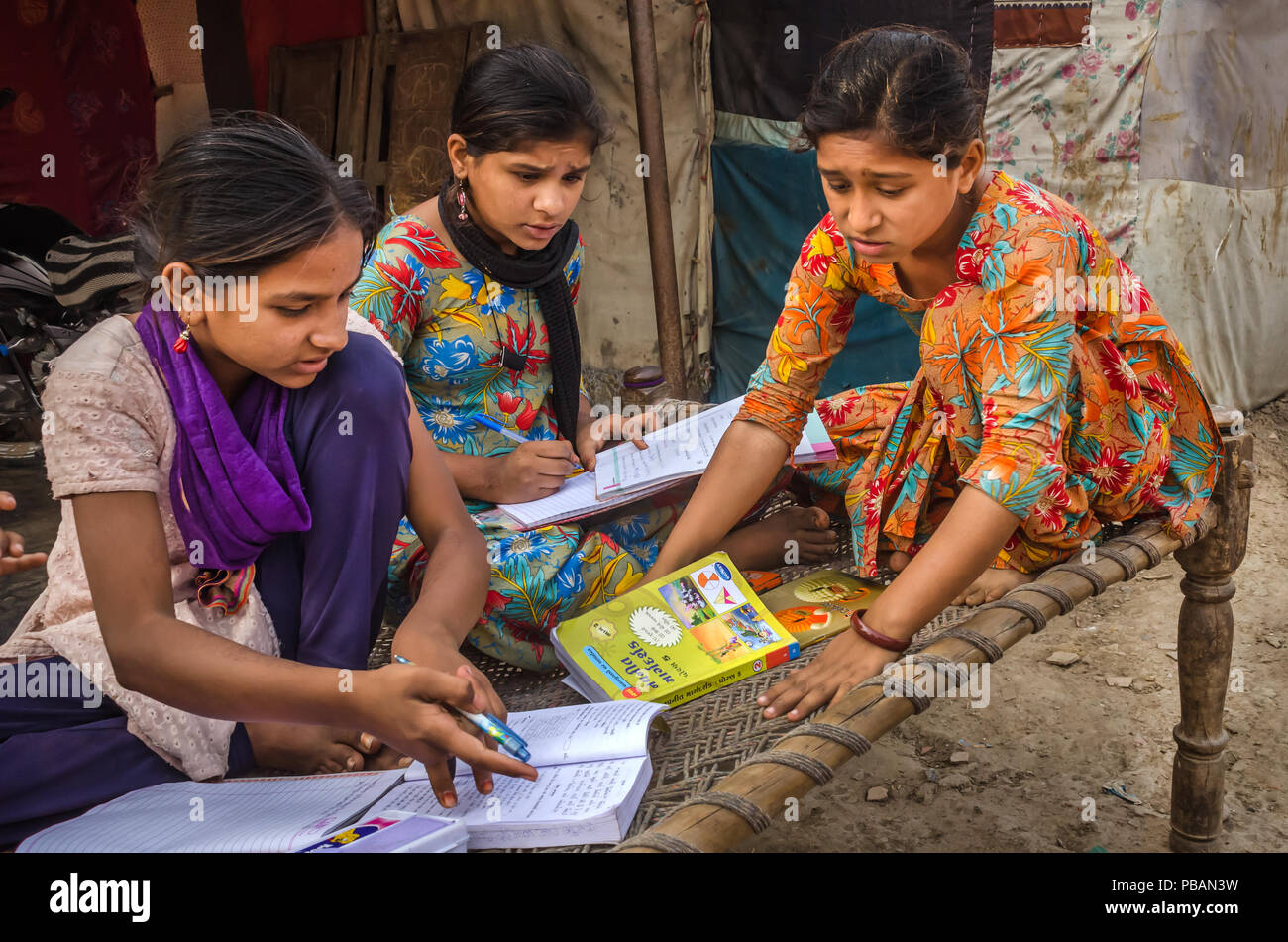 AHMEDABAD, INDE - Le 10 décembre 2017 : l'école de filles non identifié à l'origine ethnique Indien assis sur lit bébé fait ses devoirs avec les livres et les cahiers d'exercices. Banque D'Images