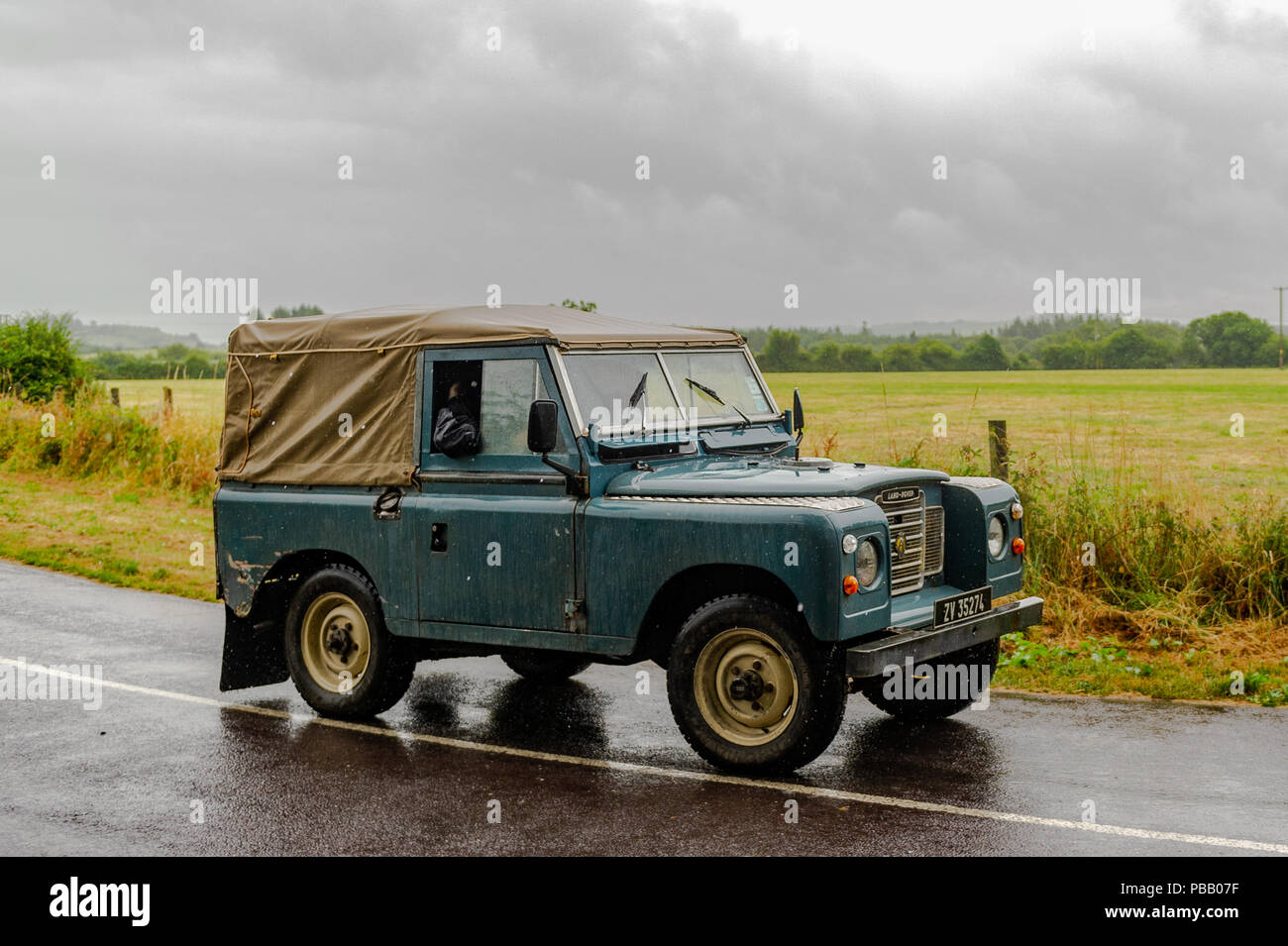 Ancien 1967 Land Rover Series II entraîne le long d'une route de campagne près de 03320, West Cork, Irlande sur une journée pluvieuse avec copie espace. Banque D'Images