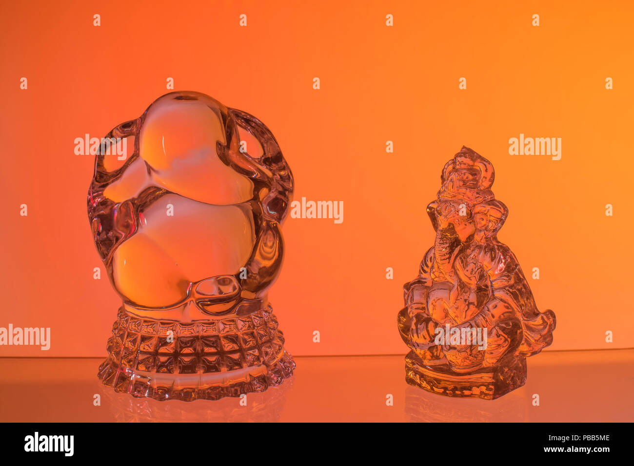 Deux idoles de Ganesh le divin Seigneur à tête d'éléphant dieux hindous faits de verre et adoré par les Indiens conservés contre fond jaune orange rouge Banque D'Images