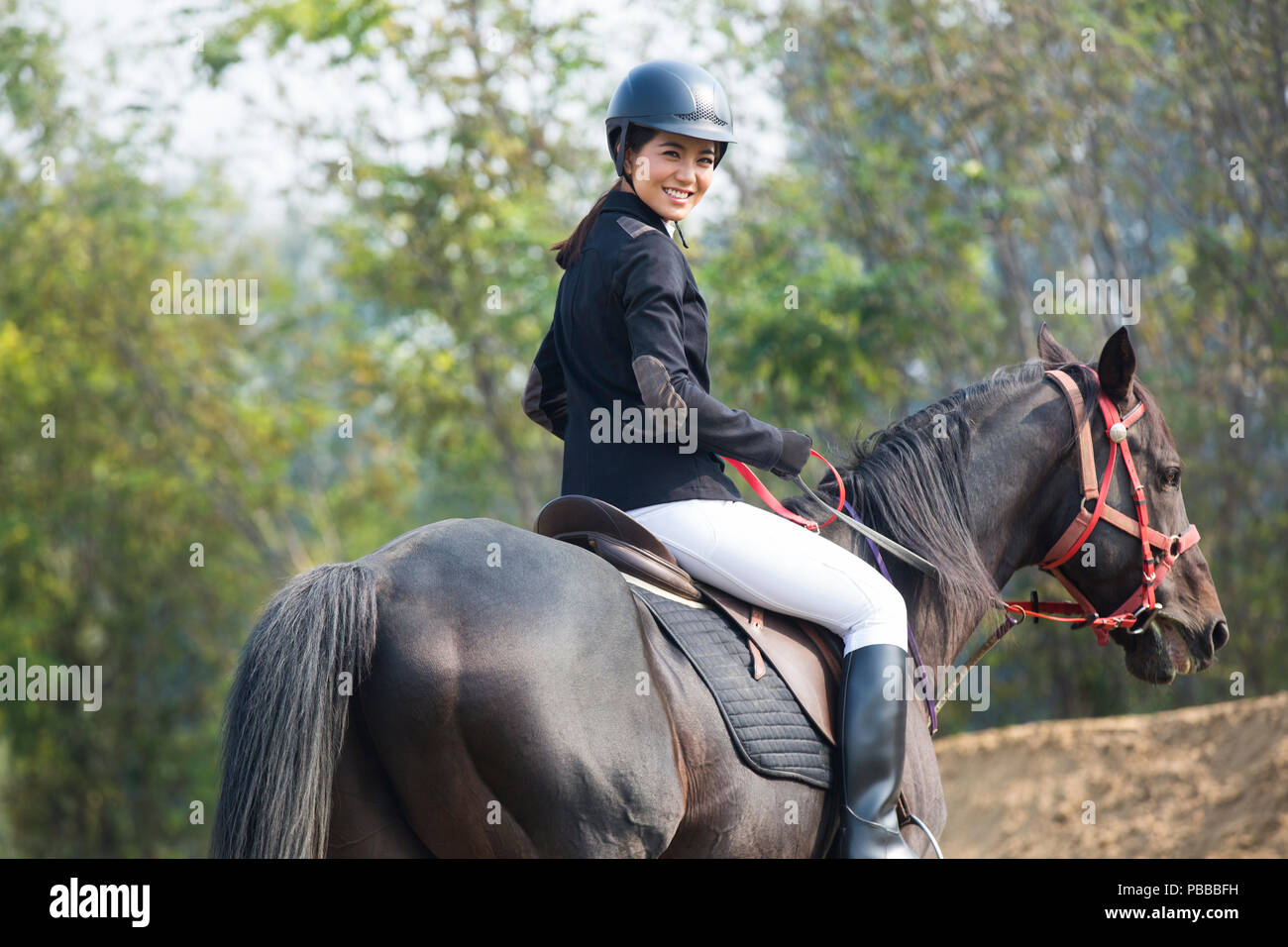 Cheerful young Chinese woman riding horse Banque D'Images