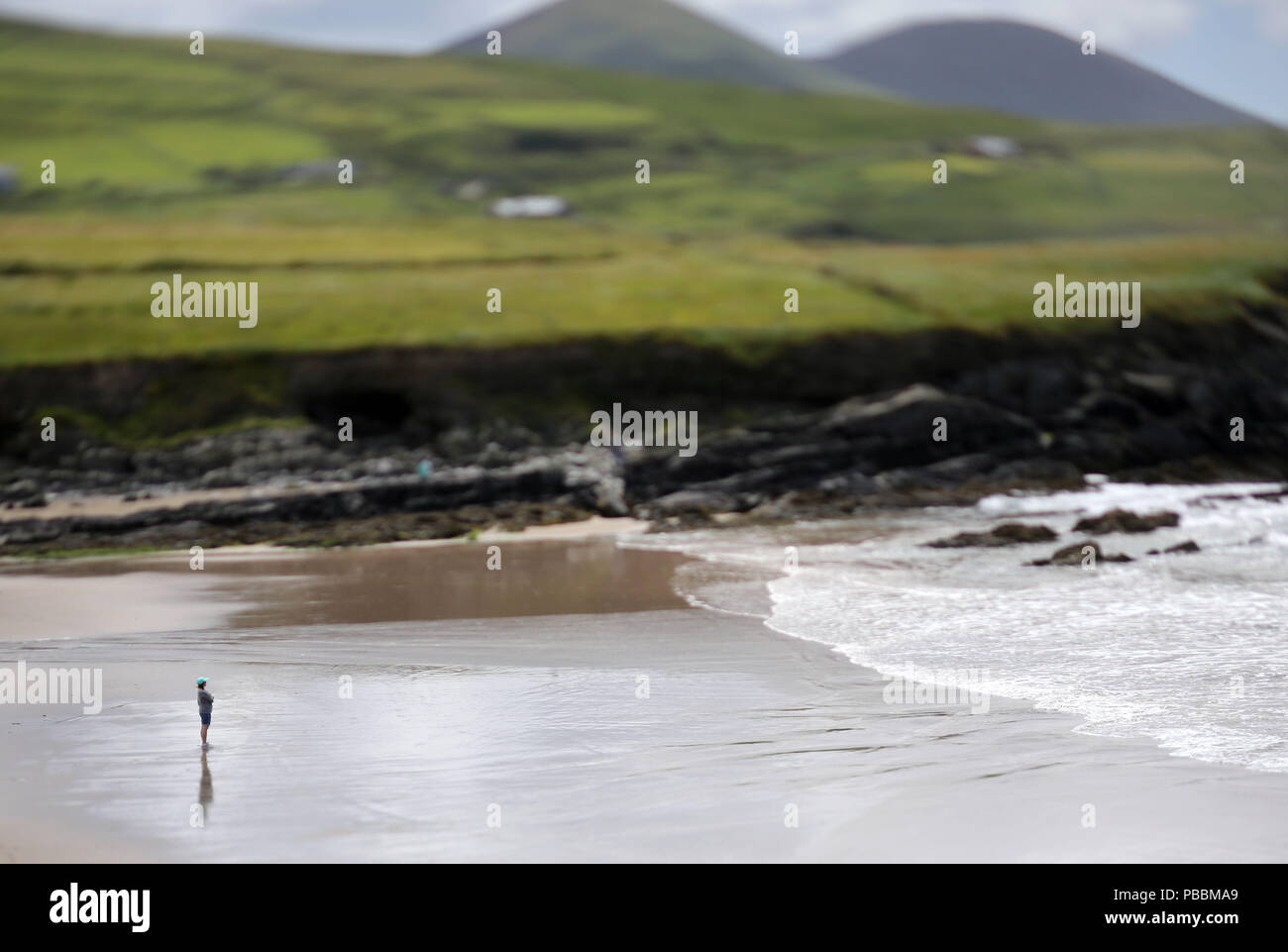 Figure solitaire observe le rouleau des vagues sur une plage de l'océan Atlantique en Irlande. Banque D'Images