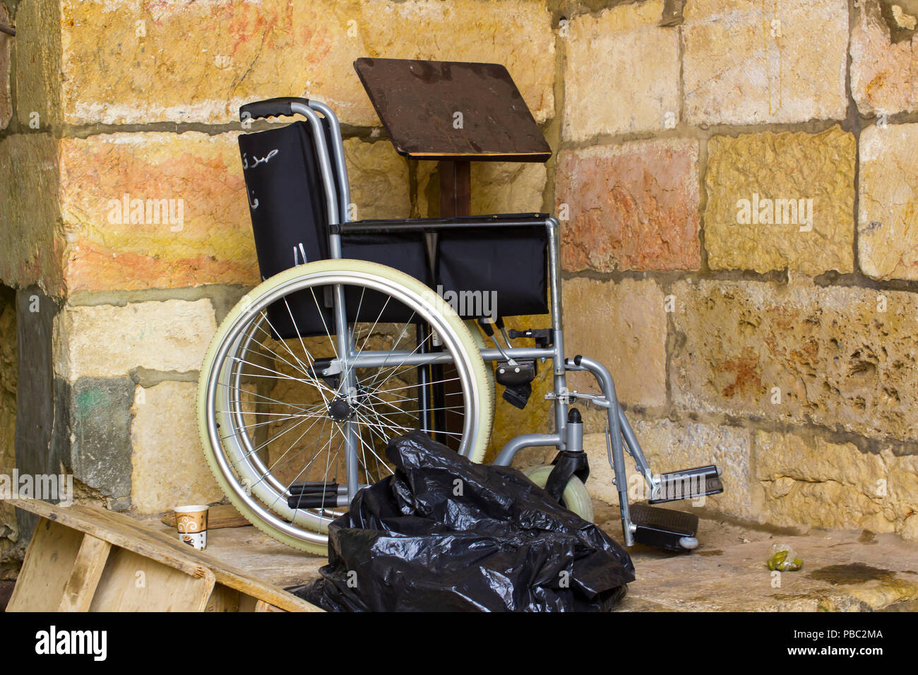 Un fauteuil roulant plié dans un coin gauche avec les ordures et autres detritis à la sortie nord du Dôme du rocher sur le mont du Temple à Jérusalem site ISR Banque D'Images